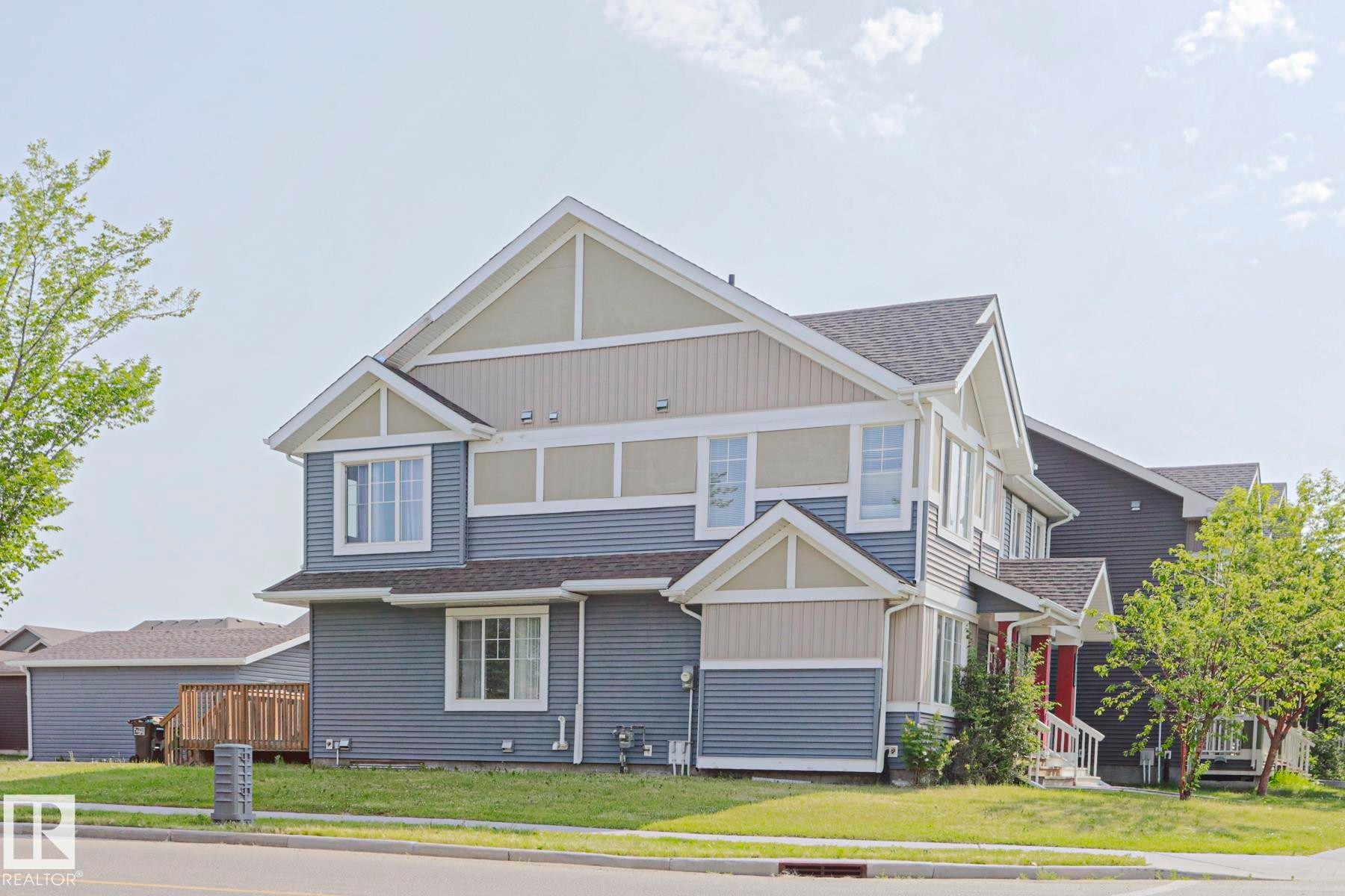 Multi-level residence featuring a blue and tan siding exterior with white trim - 489 Orchards Boulevard Sw, Edmonton, AB - Outdoor With Facade