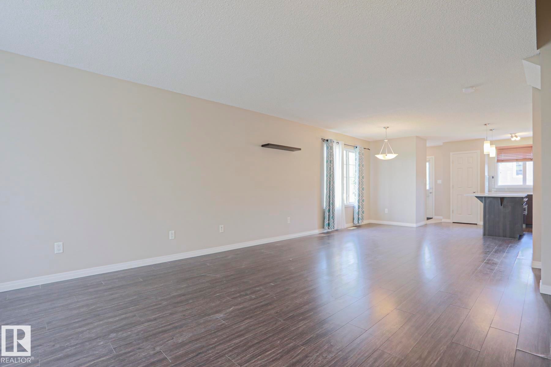 Spacious open-concept living area featuring wood-finish flooring, neutral wall tones, and recessed lighting - 489 Orchards Boulevard Sw, Edmonton, AB - Indoor