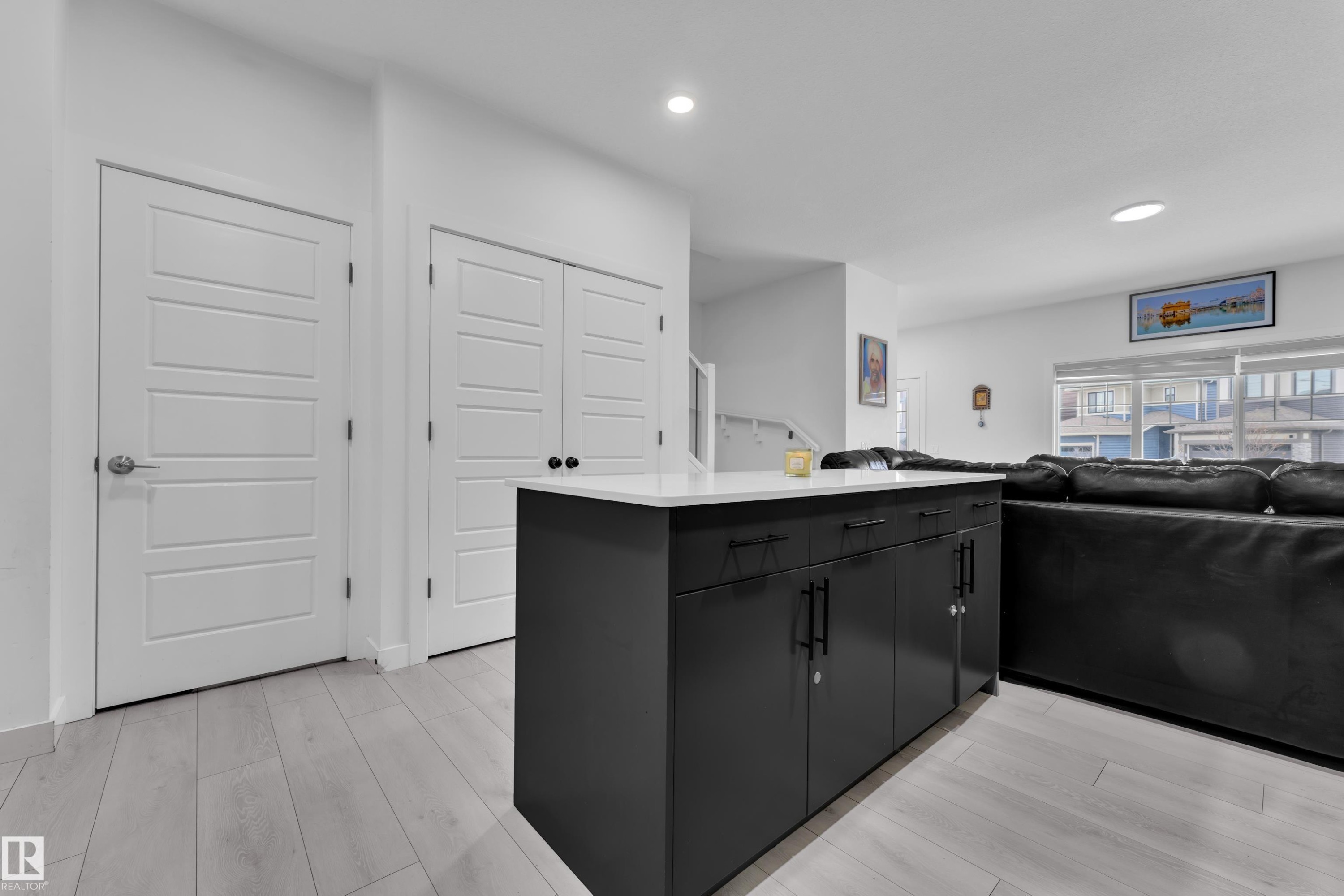 Modern kitchen island with a white countertop and dark cabinetry, complementing the light wood-finish flooring - 1645 Plum Circle Circle Sw, Edmonton, AB - Indoor