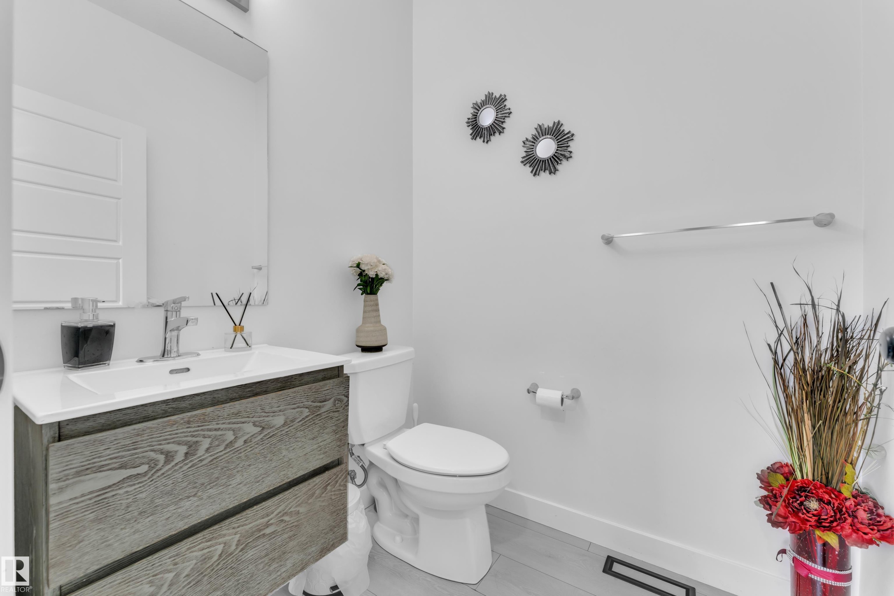 Modern bathroom featuring a floating wood-finish vanity with an integrated white sink, chrome faucet, and rectangular wall-mounted mirror - 1645 Plum Circle Circle Sw, Edmonton, AB - Indoor Photo Showing Bathroom