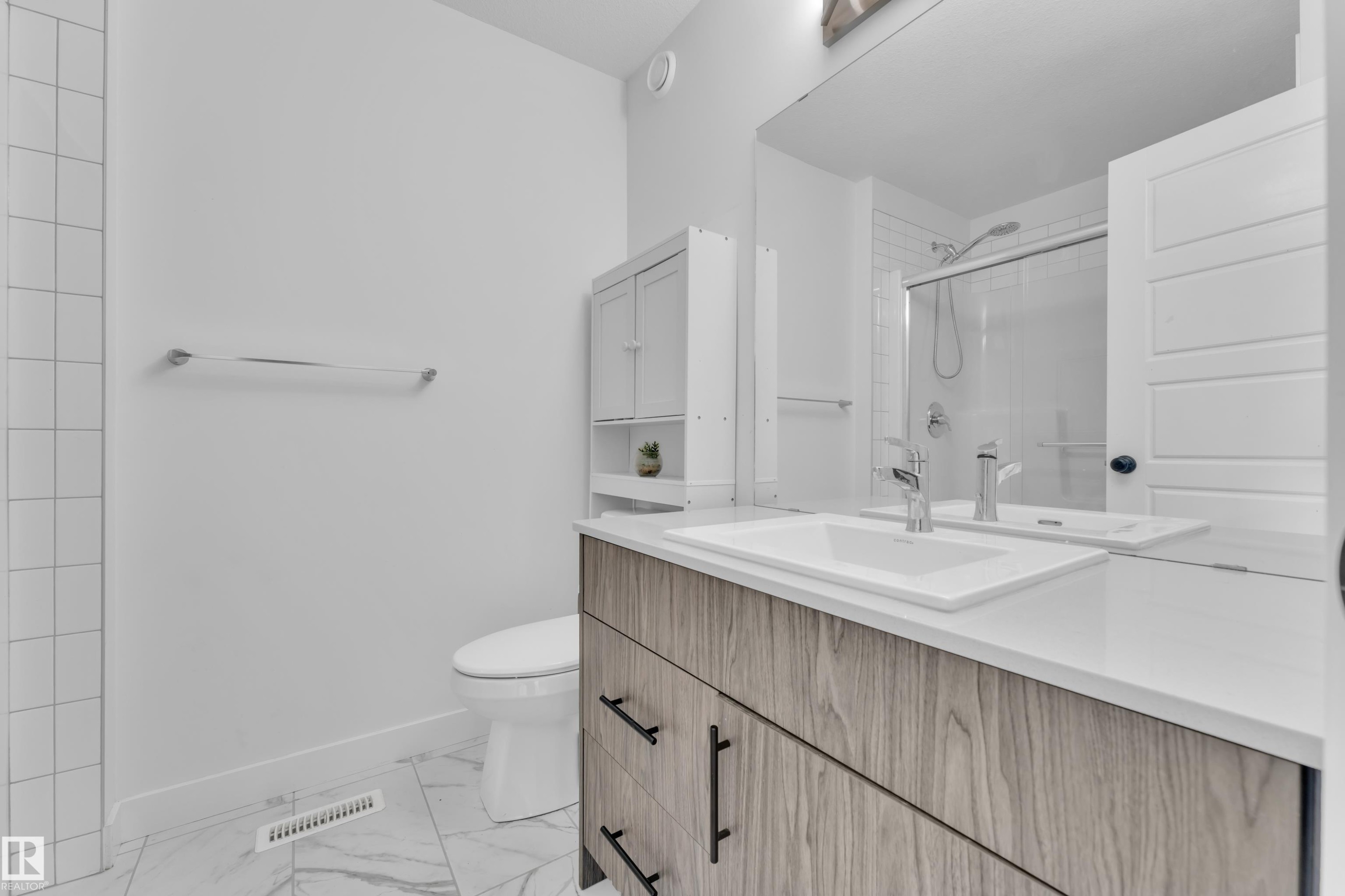 Modern bathroom featuring a wood-finish vanity with matte black hardware, a rectangular undermount sink, and a white countertop - 1645 Plum Circle Circle Sw, Edmonton, AB - Indoor Photo Showing Bathroom
