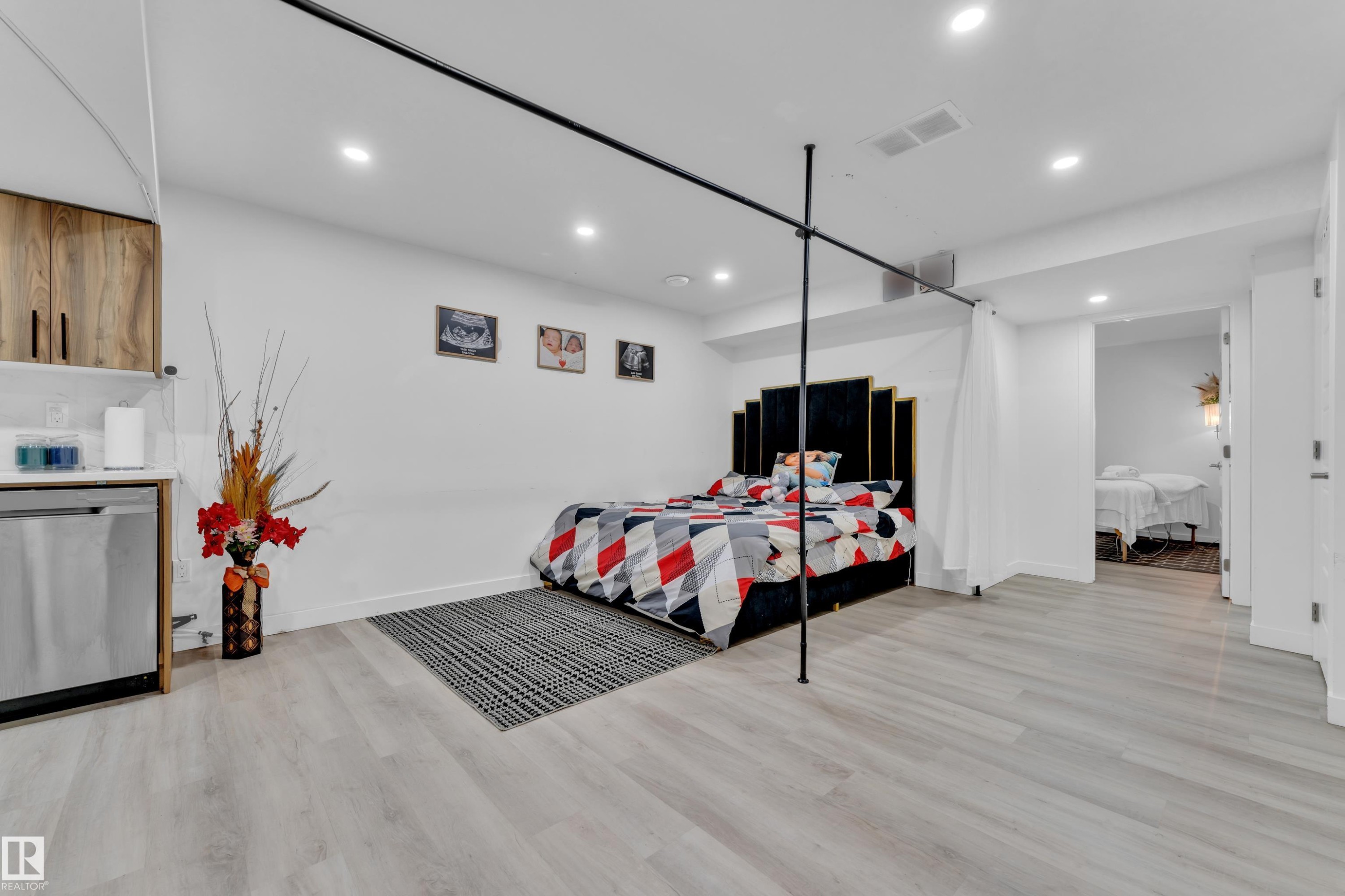 Spacious room featuring light wood-finish flooring, recessed lighting, a built-in kitchenette with wood cabinetry, and a stainless steel appliance - 1645 Plum Circle Circle Sw, Edmonton, AB - Indoor Photo Showing Other Room