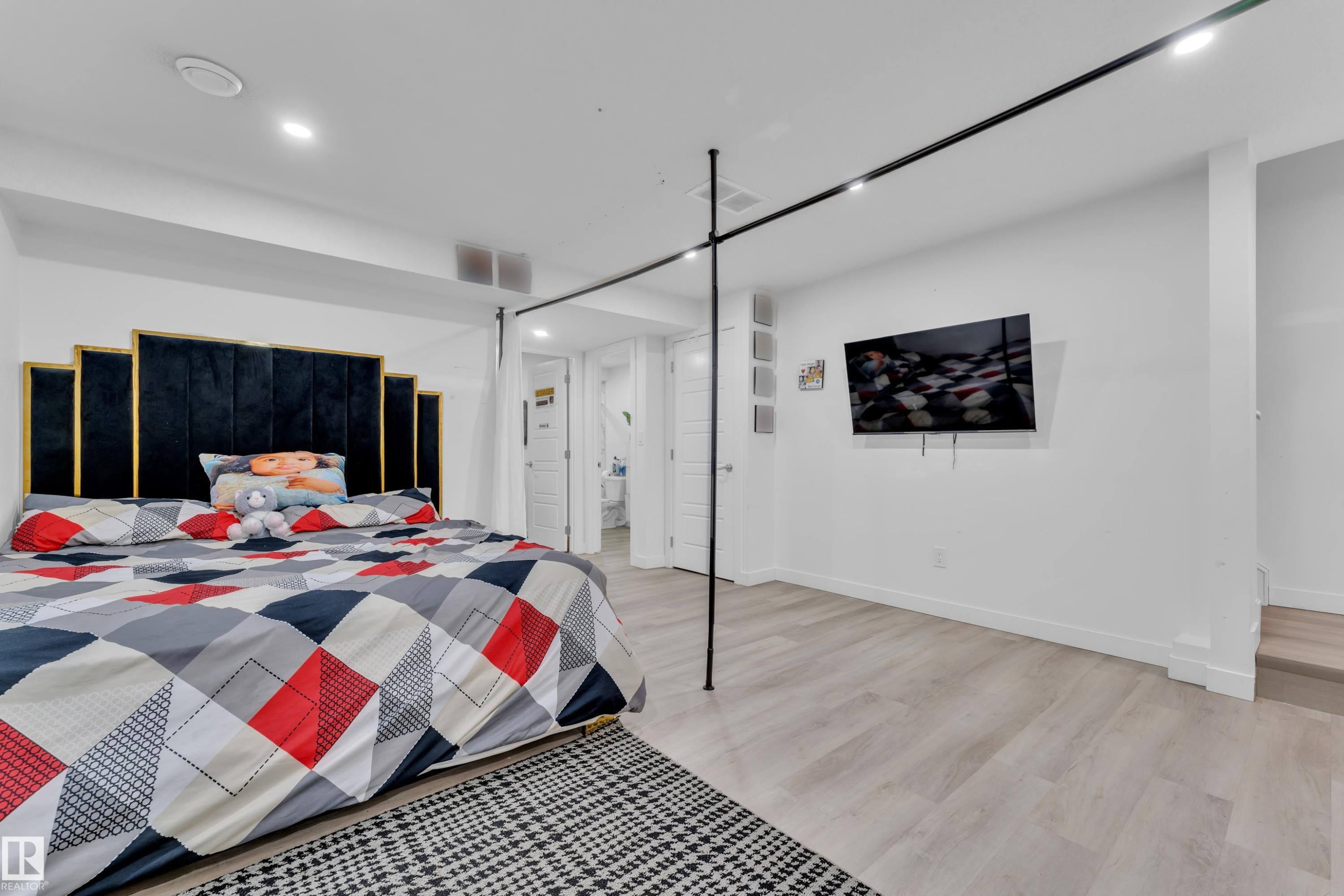Spacious room featuring light wood-finish flooring, recessed lighting, and a modern track lighting system - 1645 Plum Circle Circle Sw, Edmonton, AB - Indoor Photo Showing Bedroom
