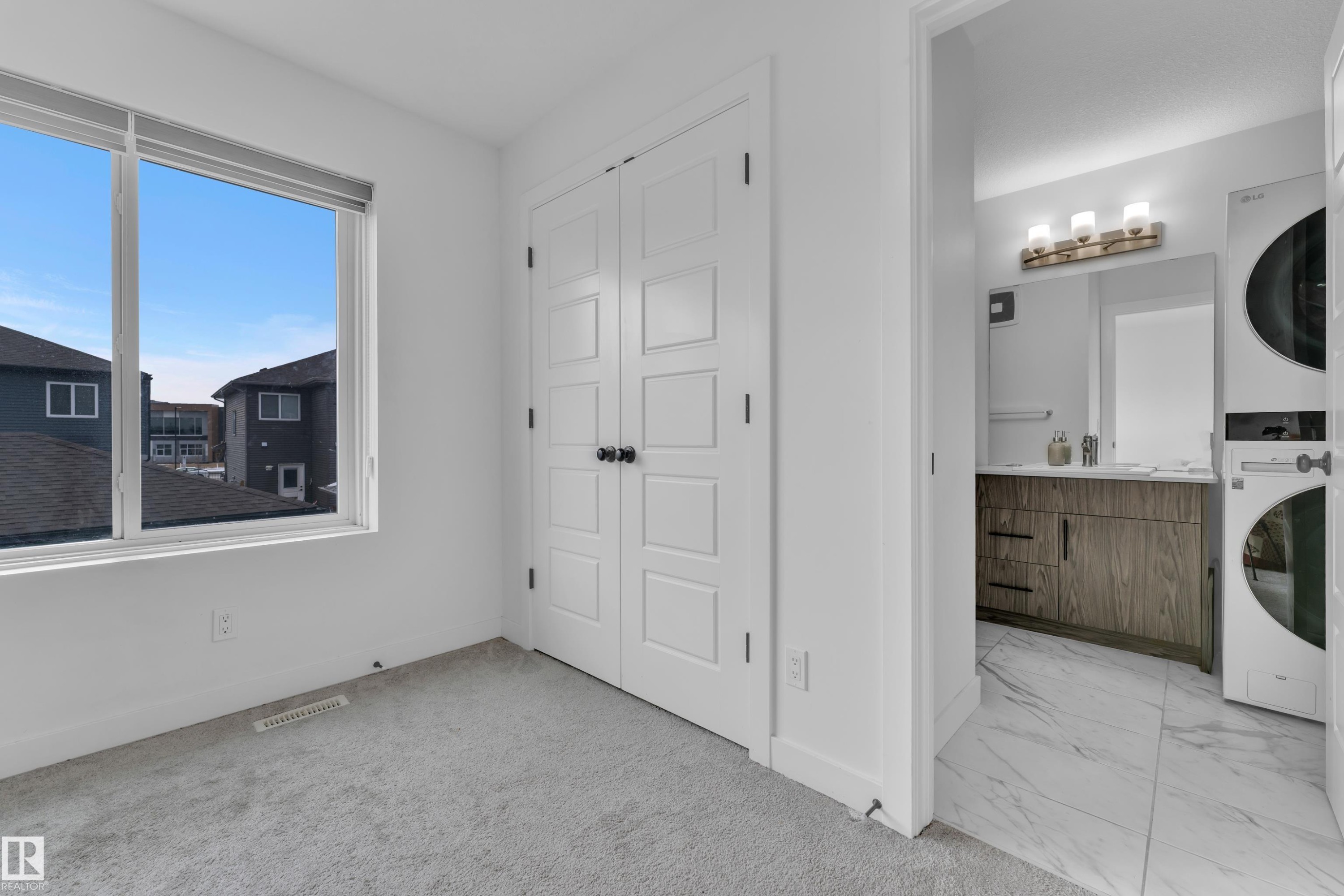 Bedroom with light gray carpeting and a large window - 1645 Plum Circle Circle Sw, Edmonton, AB - Indoor Photo Showing Laundry Room