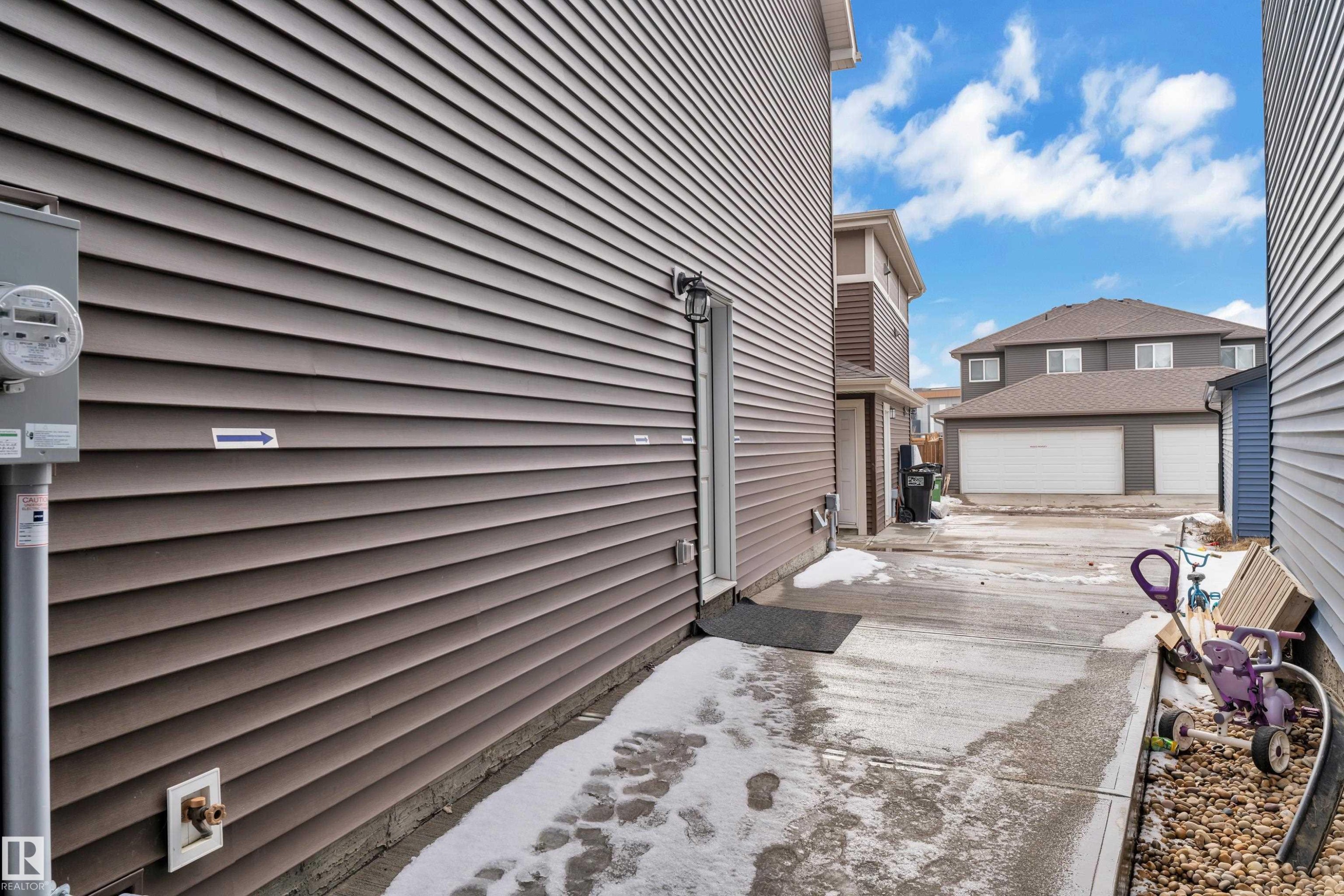 Grey siding exterior with a concrete pathway - 1645 Plum Circle Circle Sw, Edmonton, AB - Outdoor