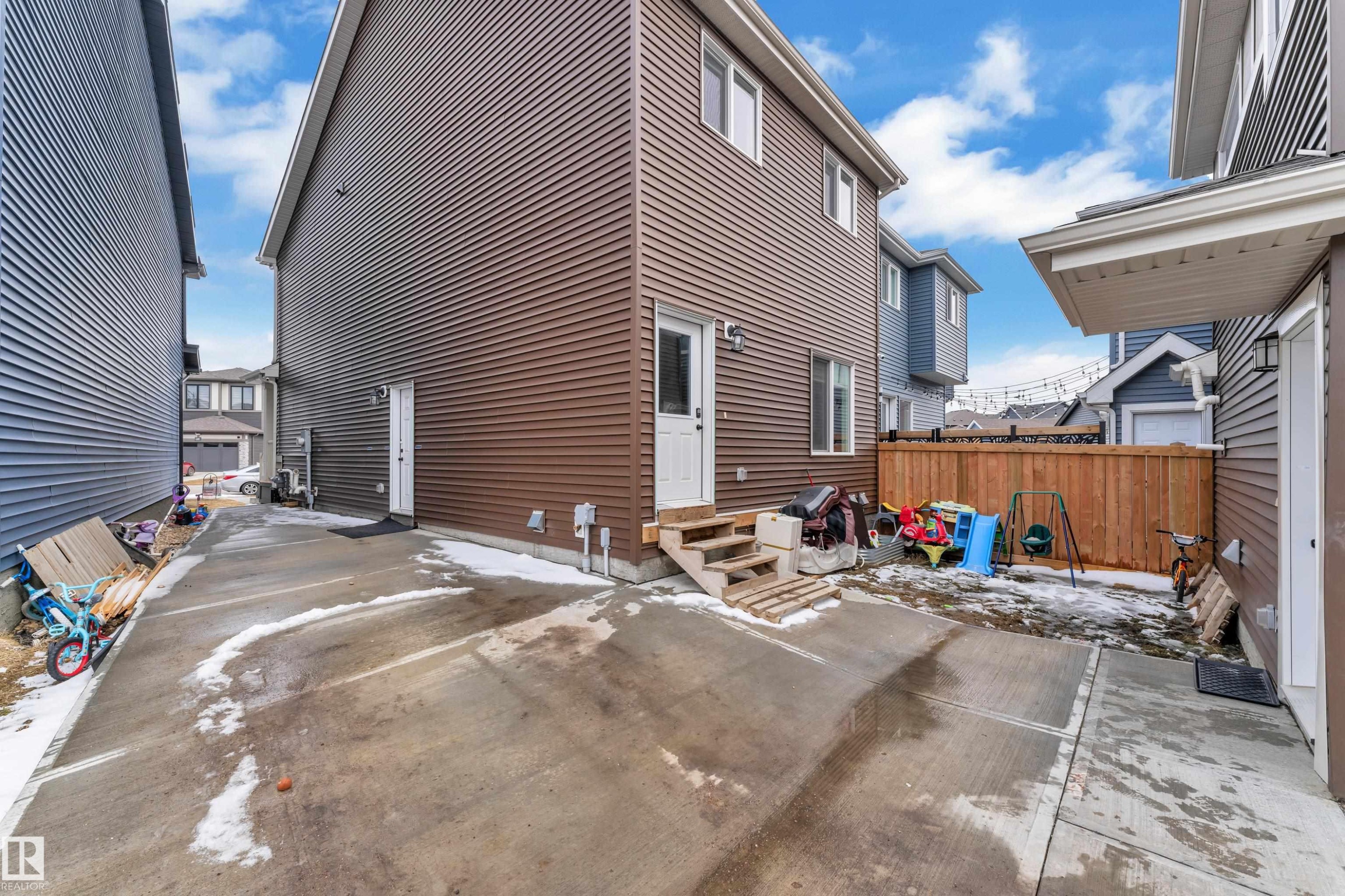 Rear exterior featuring brown horizontal siding, a private entry, and concrete patio - 1645 Plum Circle Circle Sw, Edmonton, AB - Outdoor