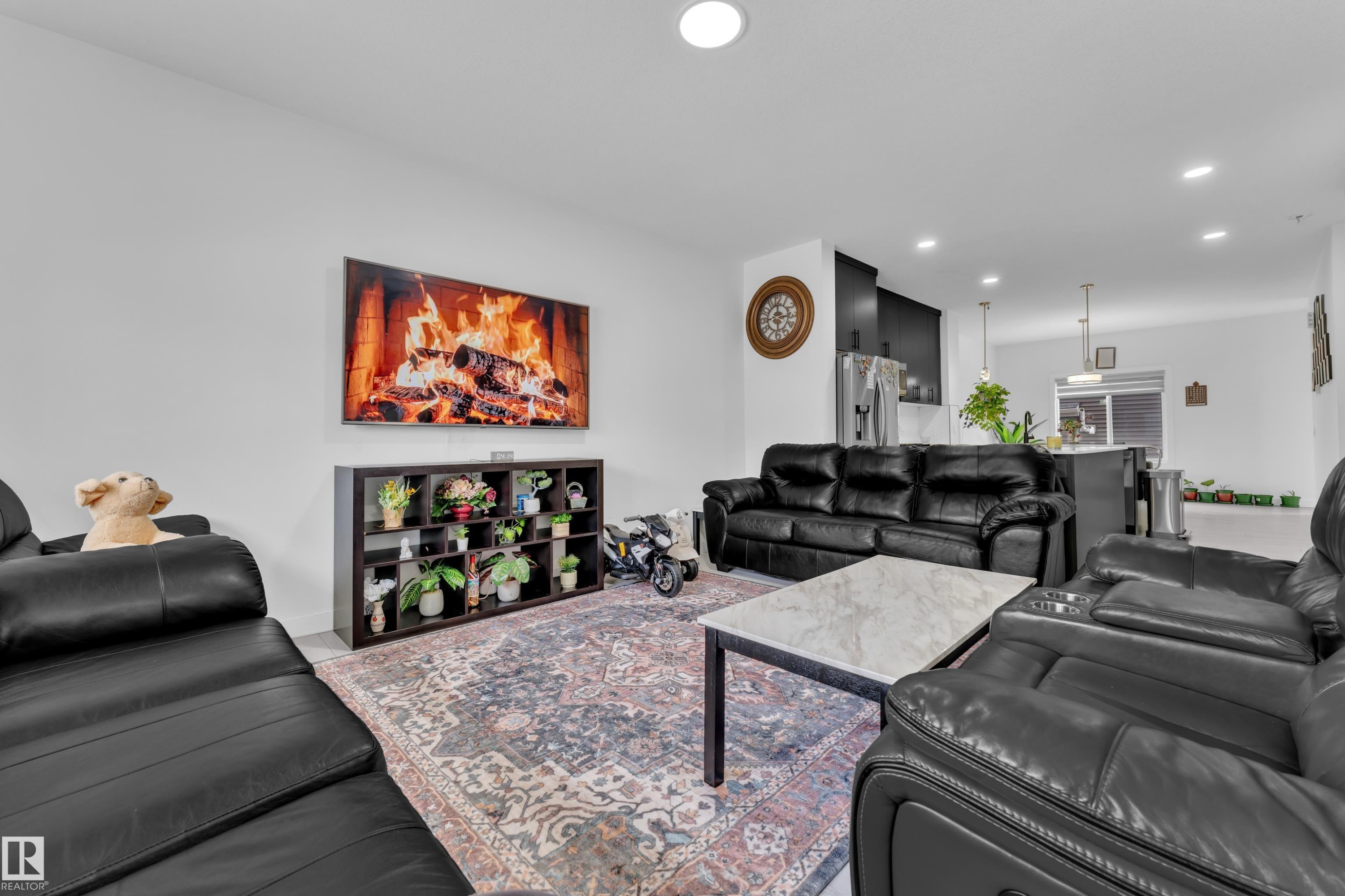 Open-concept living area with recessed lighting, a large wall-mounted display, and a decorative storage unit - 1645 Plum Circle Circle Sw, Edmonton, AB - Indoor Photo Showing Living Room