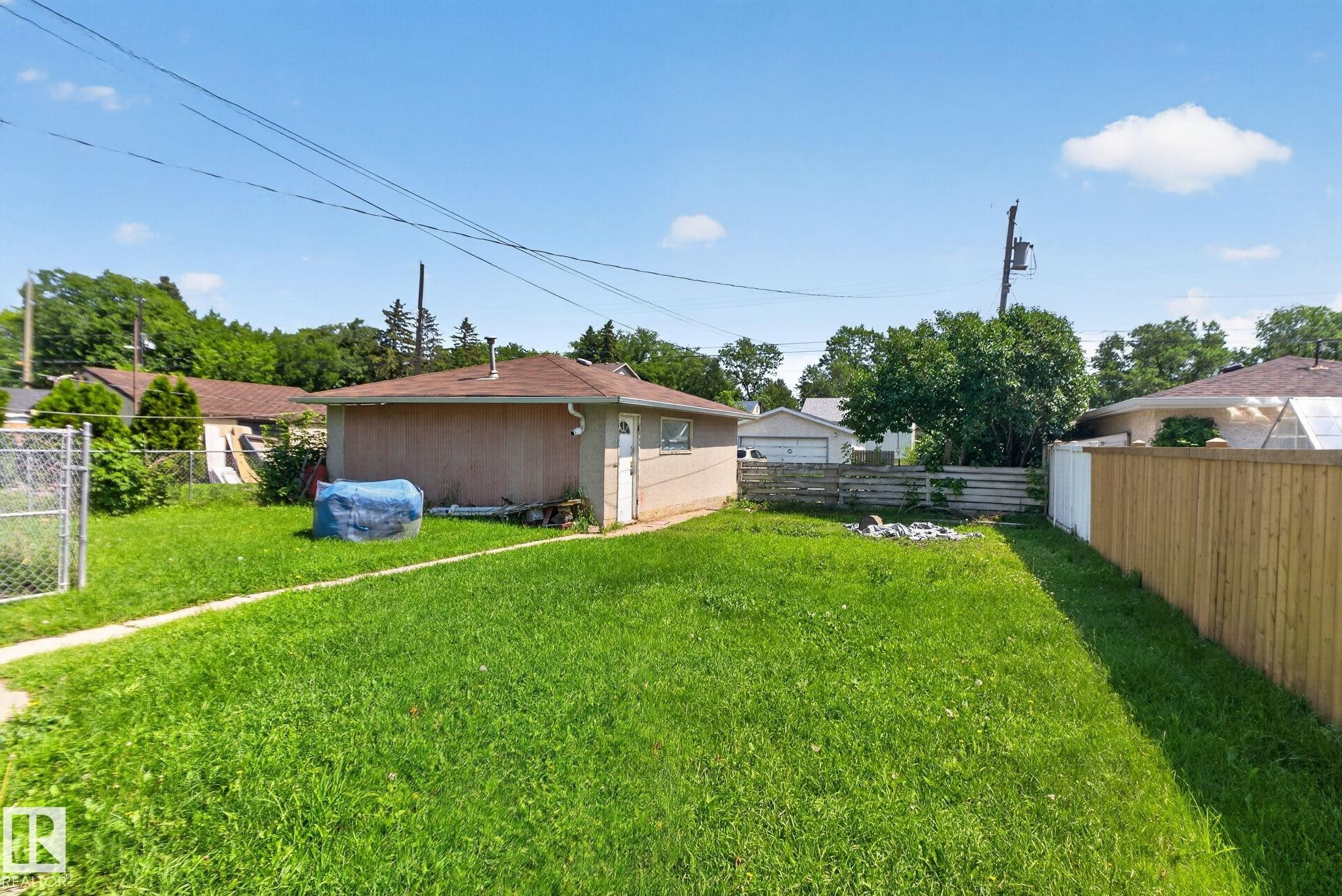Expansive green lawn with a detached auxiliary structure featuring a shingle roof and a dedicated entrance - 12229 88 Street Nw, Edmonton, AB