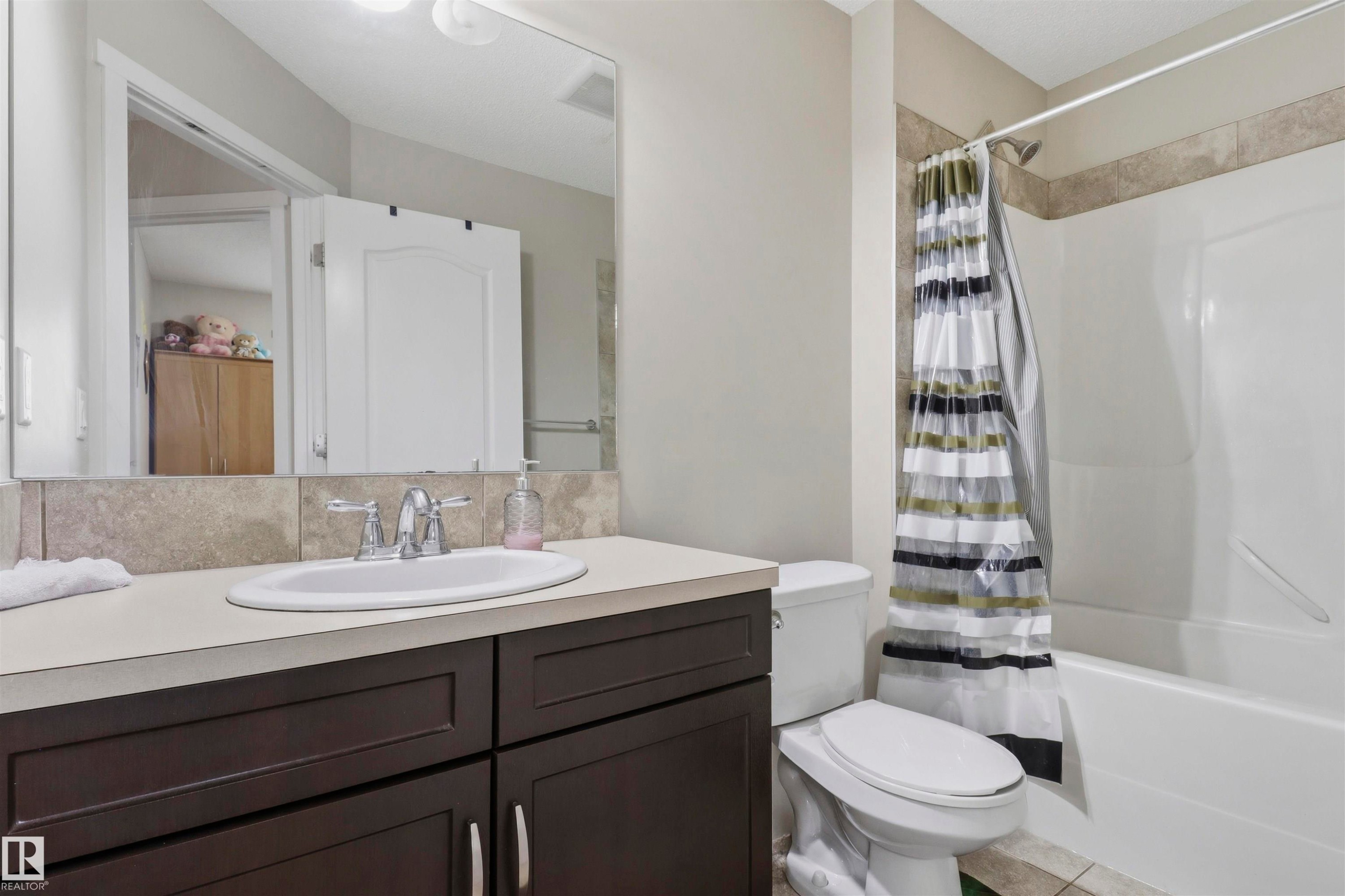 Bathroom featuring a dark wood-finish vanity with a light-toned countertop, an undermount sink, and a chrome faucet - 1528 35 Avenue Nw, Edmonton, AB - Indoor Photo Showing Bathroom