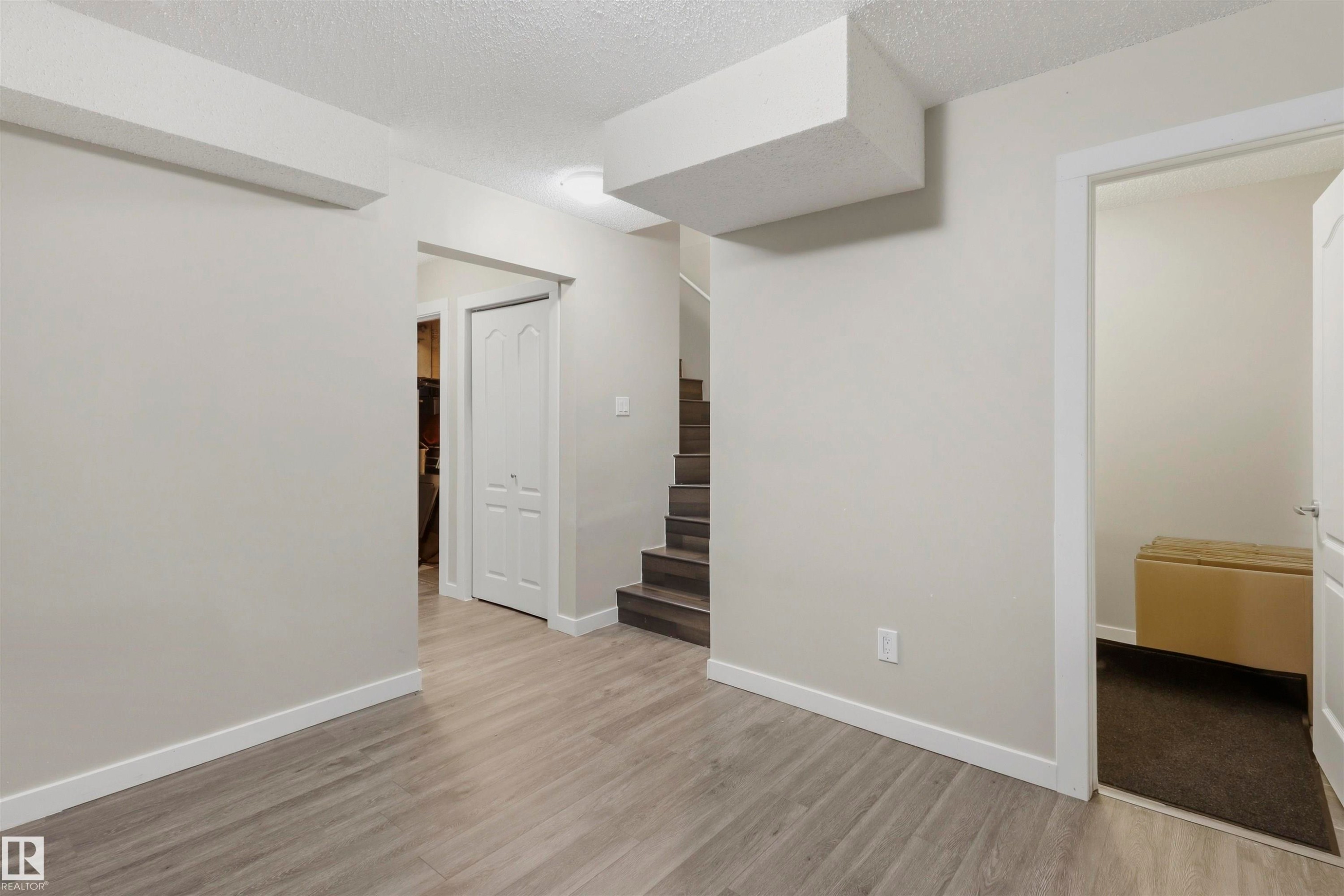 Open living area featuring light gray walls, white trim, and wood-finish flooring - 1528 35 Avenue Nw, Edmonton, AB - Indoor Photo Showing Other Room