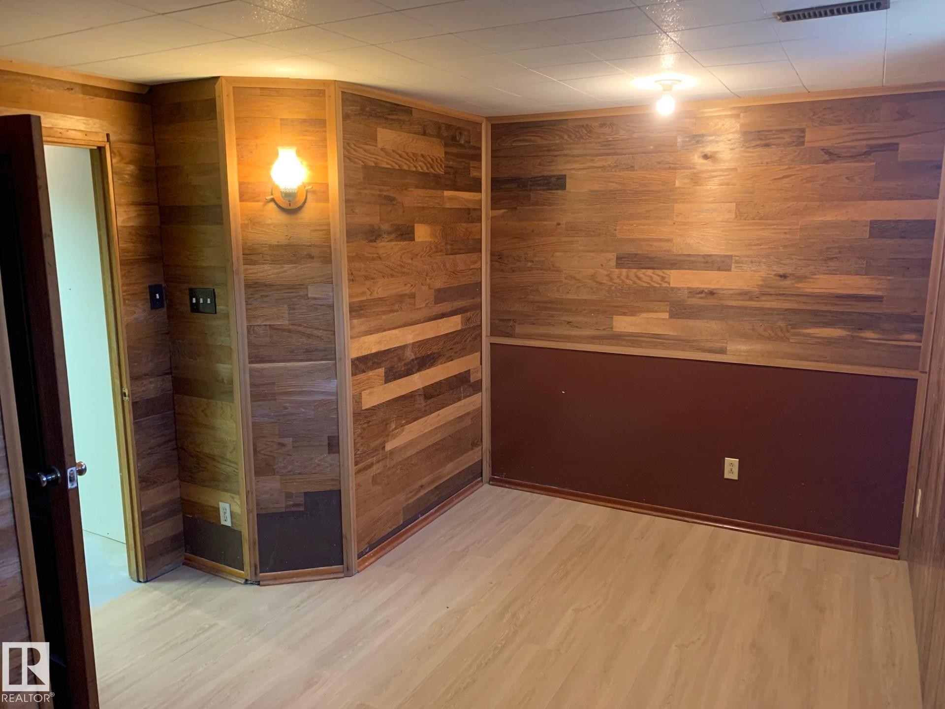Room featuring light wood-finish flooring, wood paneling, and a drop ceiling with recessed lighting - 16321 - 109A Ave Nw, Edmonton, AB - Indoor Photo Showing Other Room