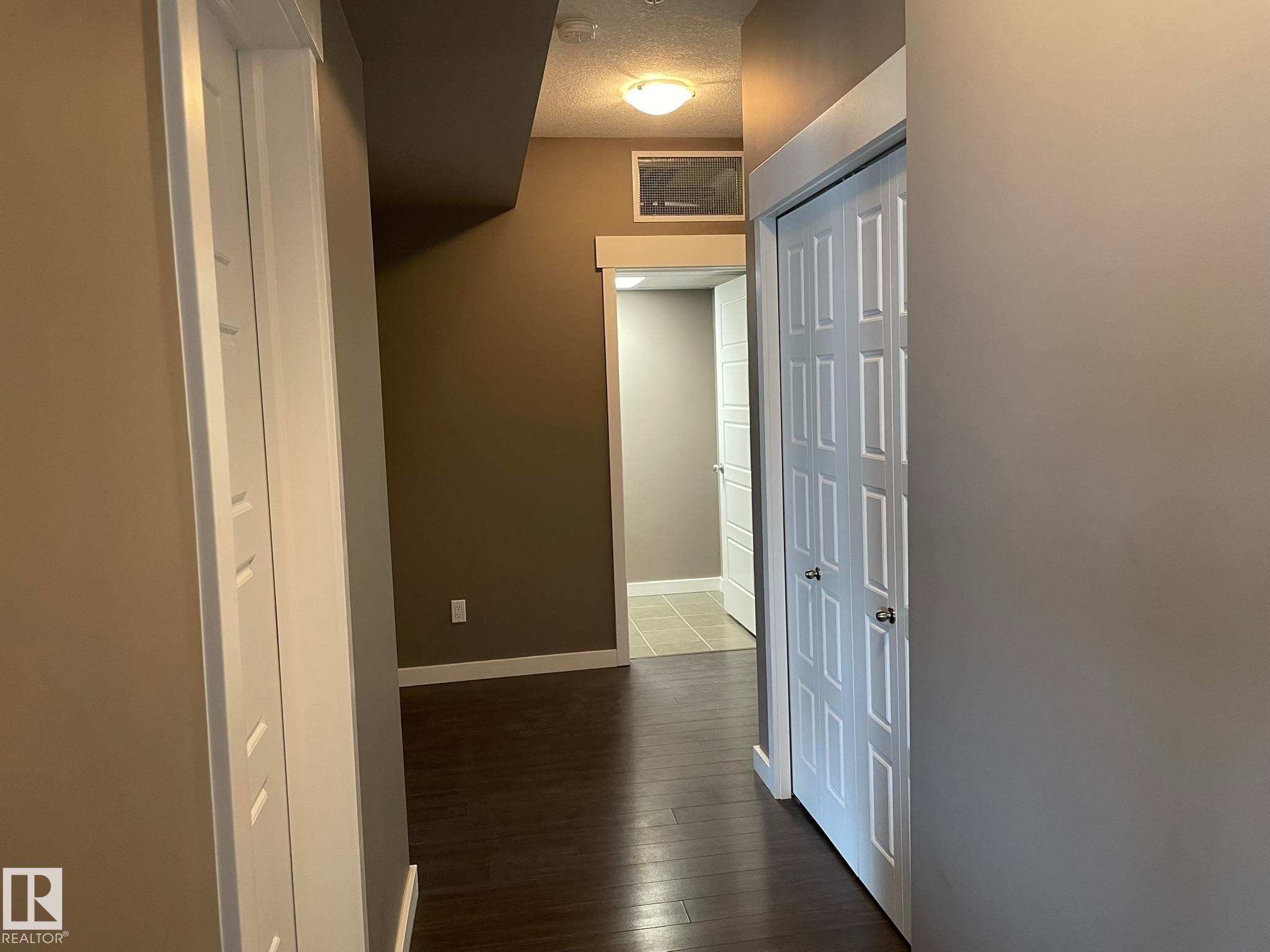 Hallway featuring wood-finish flooring, white trim, recessed lighting, and a bi-fold door - #504 10518 113 St Nw, Edmonton, AB - Indoor Photo Showing Other Room
