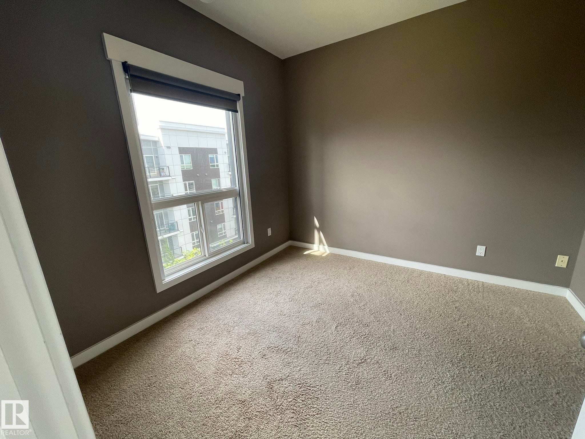 Expansive window with white trim and a roller shade - #504 10518 113 St Nw, Edmonton, AB - Indoor Photo Showing Other Room