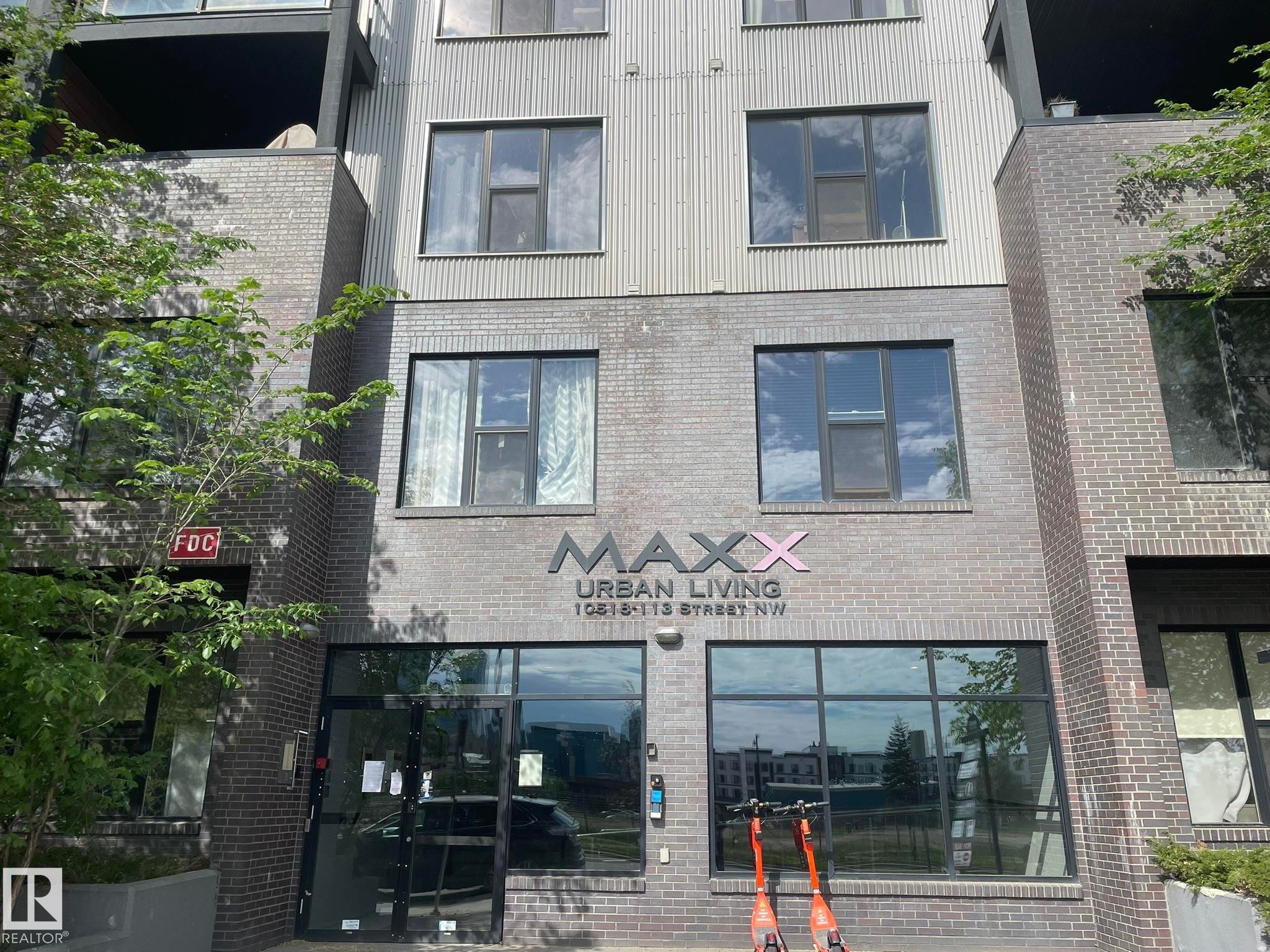 Multi-story building featuring a brick facade, large storefront windows, and upper-level balconies - #504 10518 113 St Nw, Edmonton, AB - Outdoor
