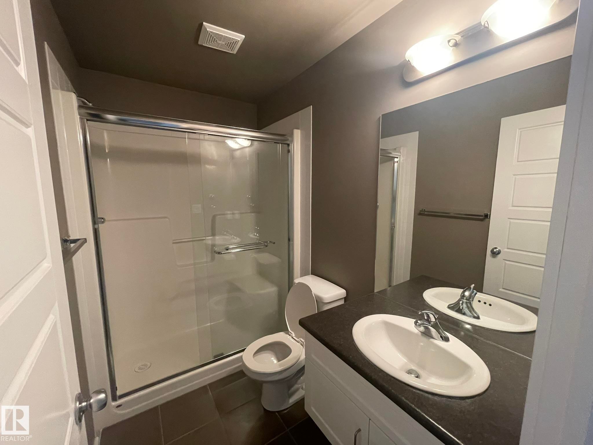 Bathroom featuring a double vanity with integrated sinks, a chrome faucet, and a large mirror - #504 10518 113 St Nw, Edmonton, AB - Indoor Photo Showing Bathroom