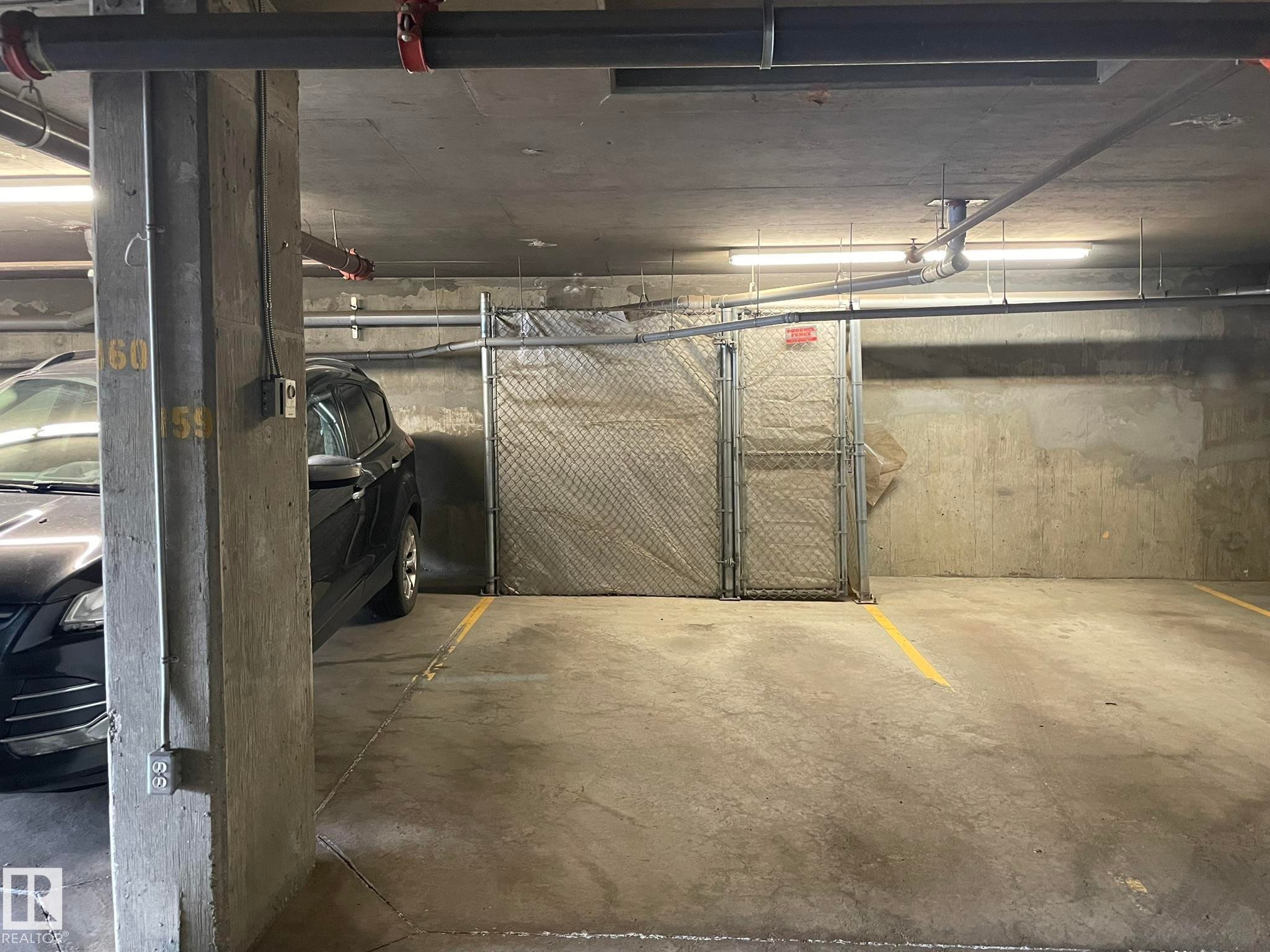 Concrete flooring with painted yellow parking space lines - #504 10518 113 St Nw, Edmonton, AB - Indoor Photo Showing Garage