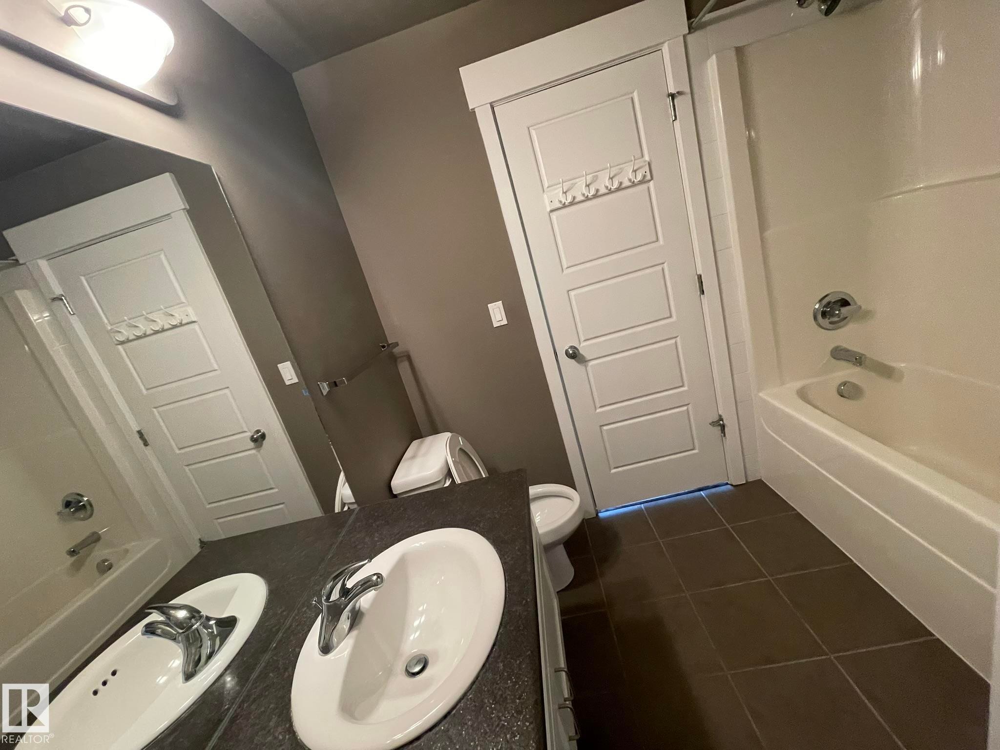 Bathroom featuring a single vanity with an oval sink, chrome faucet, and dark countertop - #504 10518 113 St Nw, Edmonton, AB - Indoor Photo Showing Bathroom
