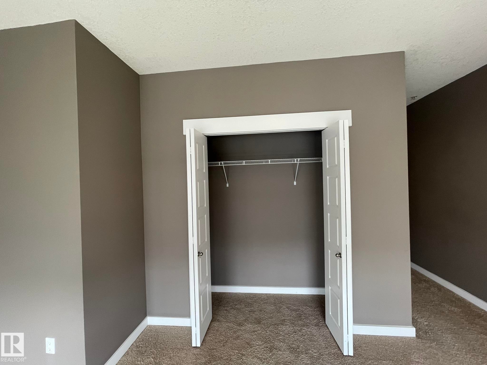 Recessed closet with bi-fold doors, wire shelving, and neutral wall paint - #504 10518 113 St Nw, Edmonton, AB - Indoor Photo Showing Other Room