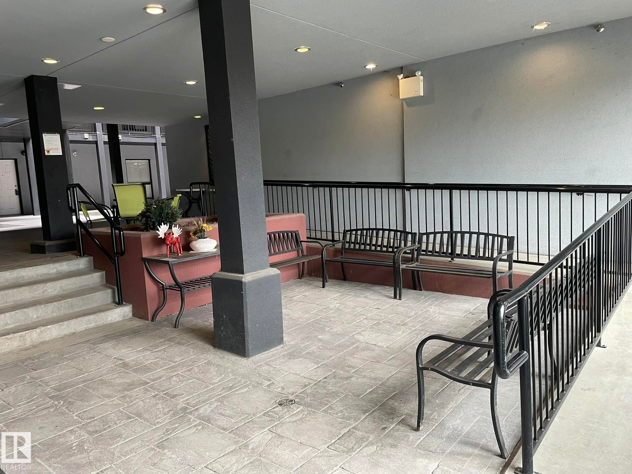 Covered outdoor patio area featuring stamped concrete flooring, black metal railings, and recessed ceiling lighting - #504 10518 113 St Nw, Edmonton, AB - Indoor Photo Showing Other Room