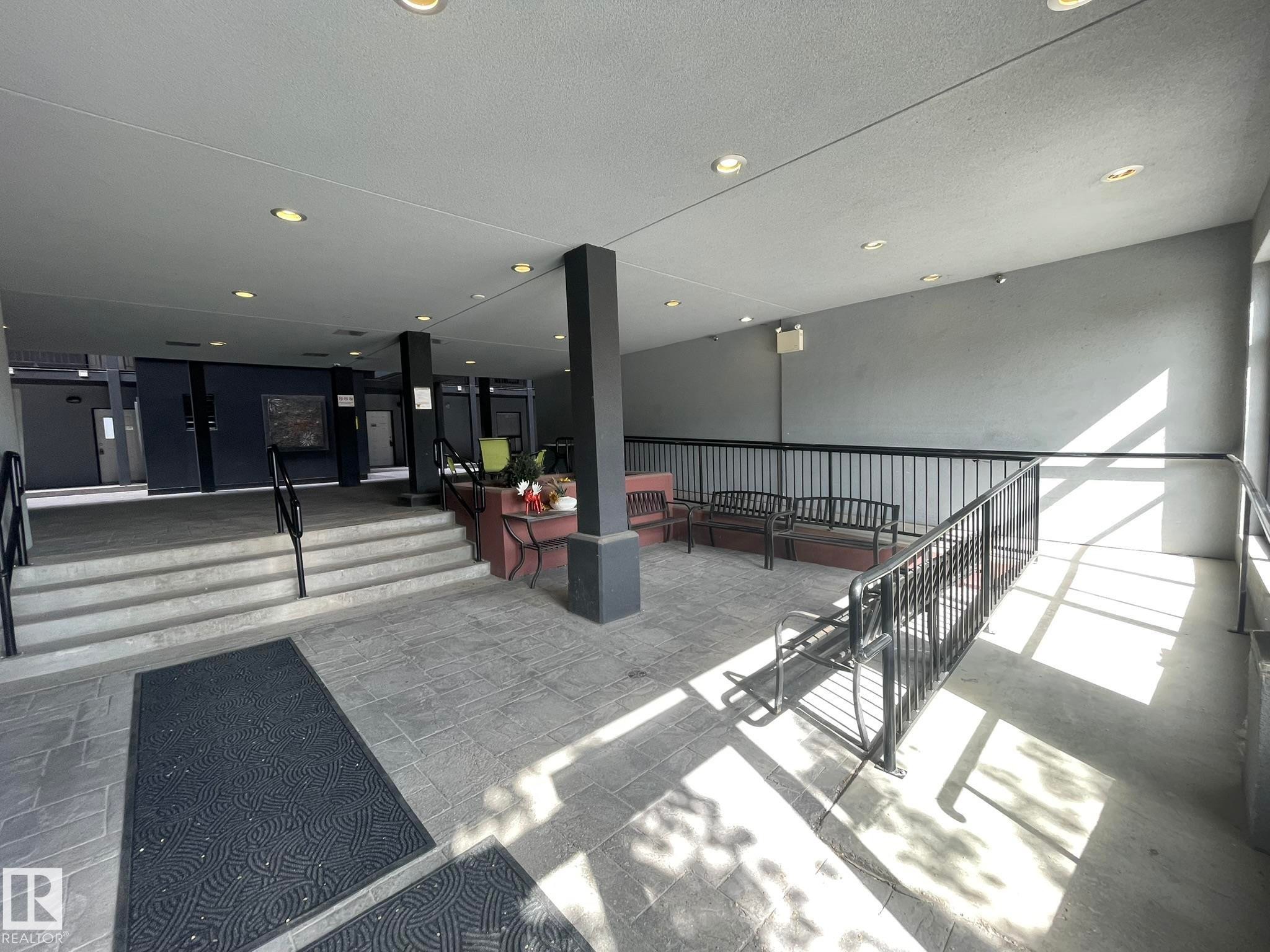 Covered outdoor common area featuring recessed lighting, a stone tile floor, and black metal railings - #504 10518 113 St Nw, Edmonton, AB - Indoor Photo Showing Other Room