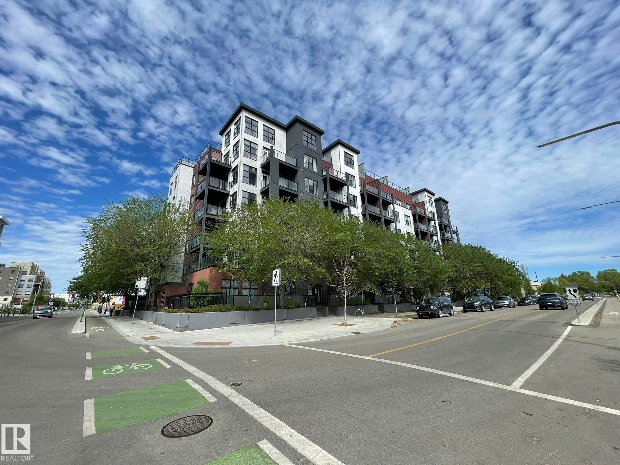 Contemporary multi-story building featuring dark gray and white facade panels with exposed brick accents - #504 10518 113 St Nw, Edmonton, AB - Outdoor With Balcony