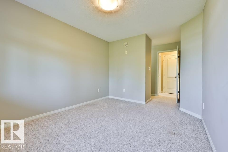 Neutral-toned wall paint and light-colored carpeting - #406 4903 47 Av, Stony Plain, AB - Indoor Photo Showing Other Room