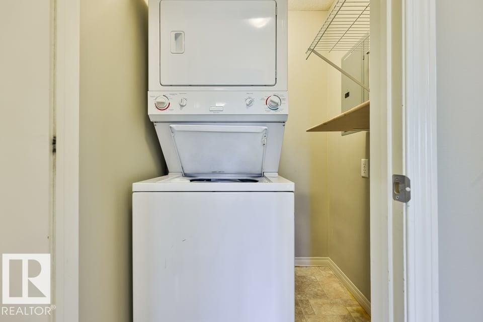 Dedicated laundry area featuring a white stackable washer and dryer unit, wire shelving, and an additional wall-mounted shelf - #406 4903 47 Av, Stony Plain, AB - Indoor Photo Showing Laundry Room