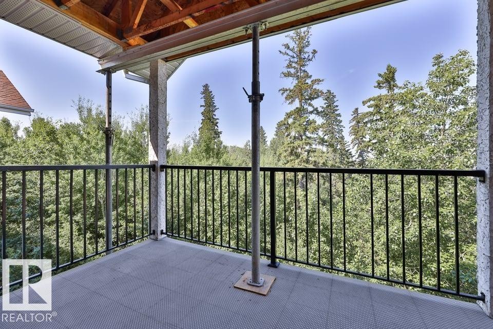Balcony featuring a black wrought iron railing, textured gray flooring, and an exposed wood beam ceiling - #406 4903 47 Av, Stony Plain, AB - Outdoor