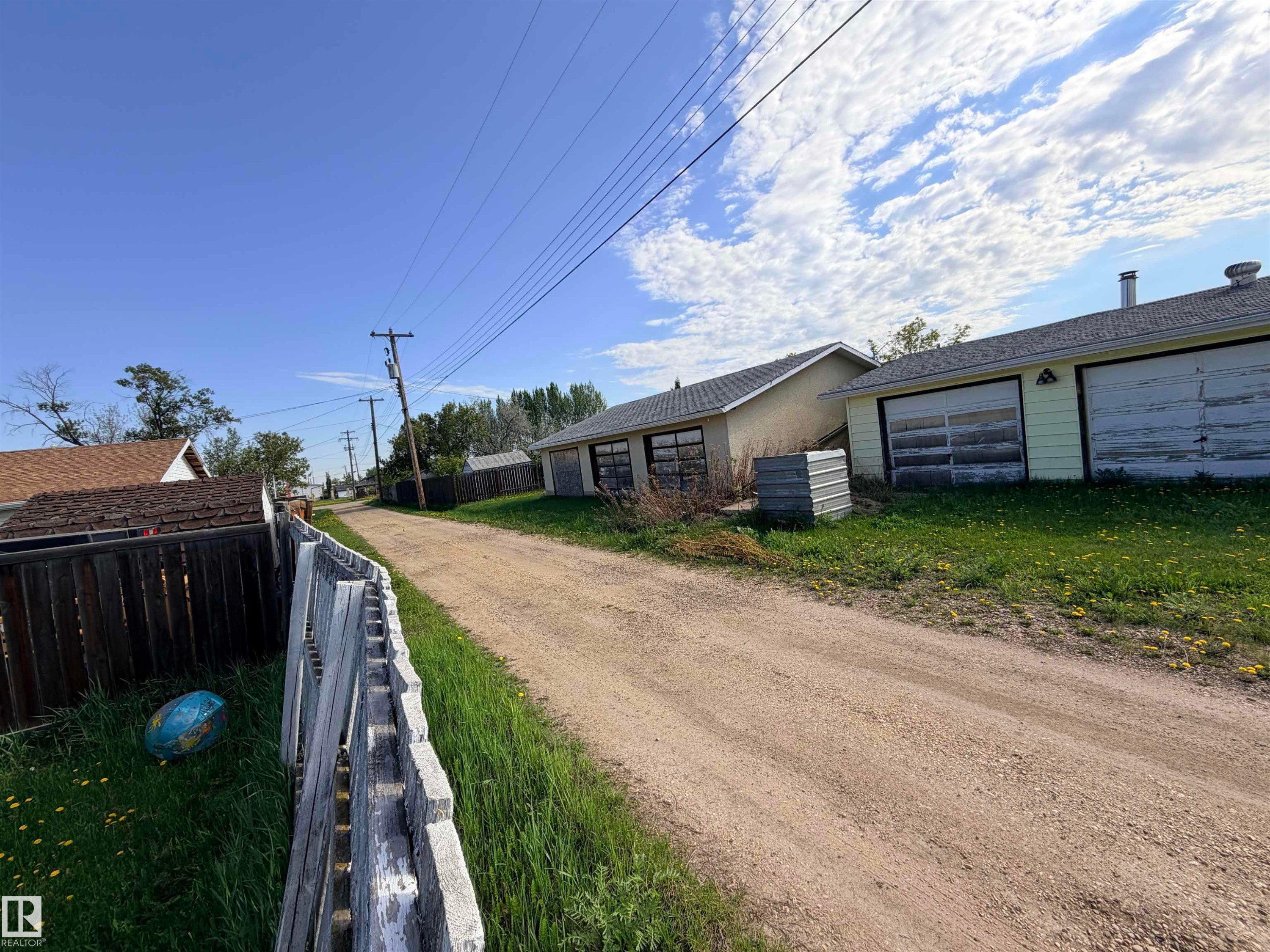 Gravel path presenting multiple detached garage structures with overhead doors - 4823 49 Street, Clyde, AB - Outdoor