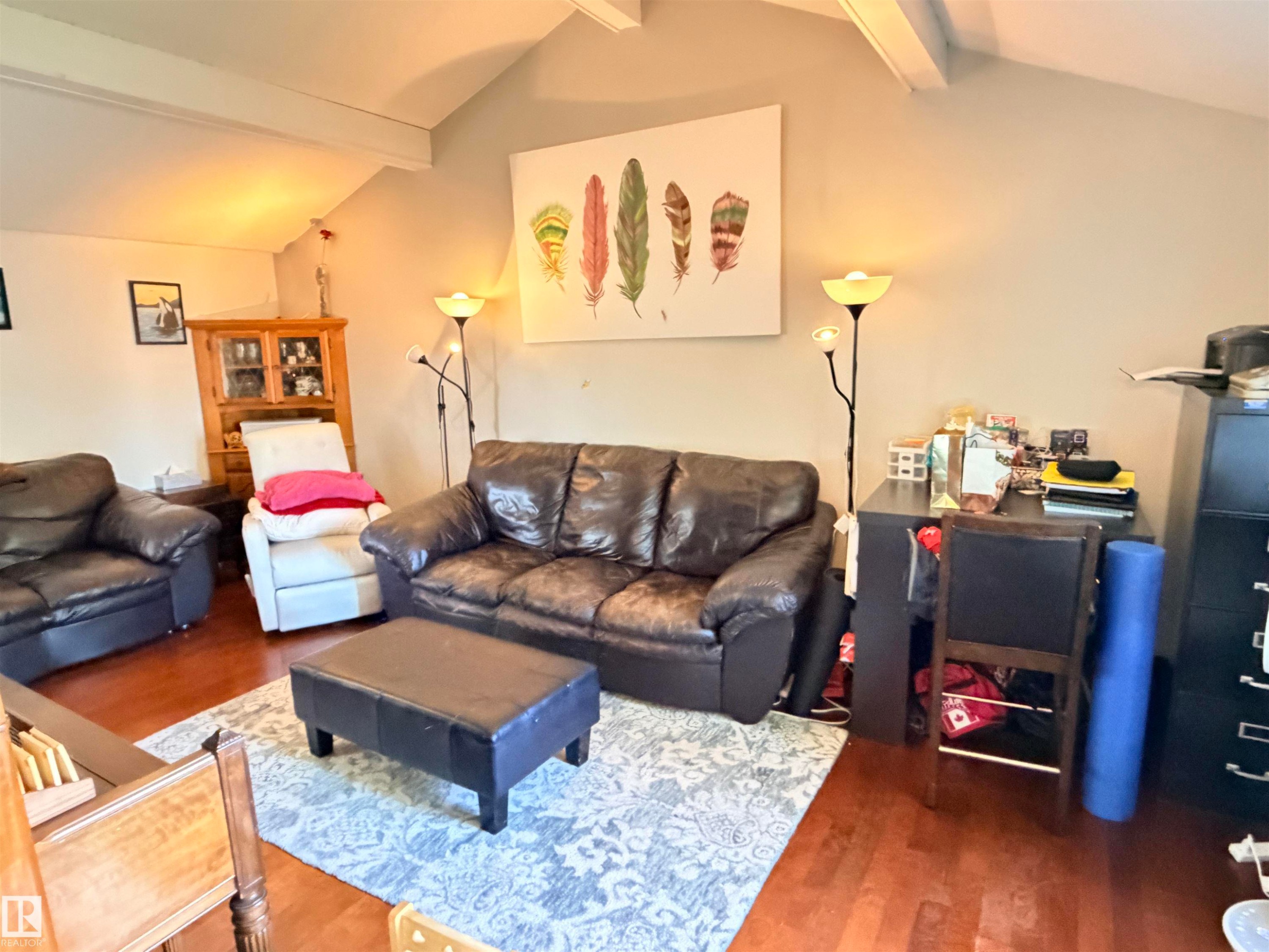 Living area featuring wood-finish flooring, vaulted ceilings with exposed beams, and a neutral wall color - 4823 49 Street, Clyde, AB - Indoor Photo Showing Living Room