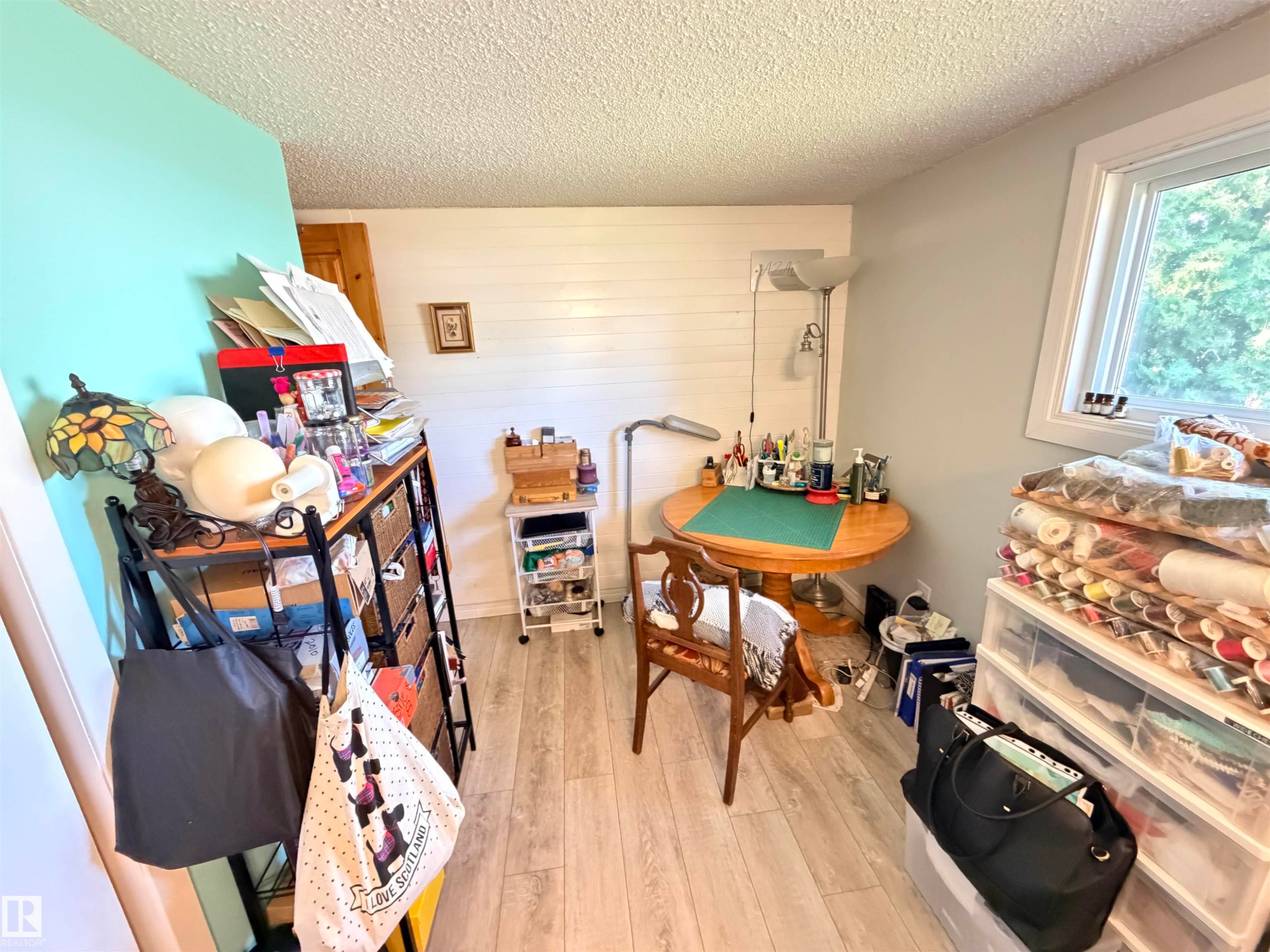 Versatile room featuring light wood-finish flooring, a bright window, and textured white shiplap paneling - 4823 49 Street, Clyde, AB - Indoor Photo Showing Other Room