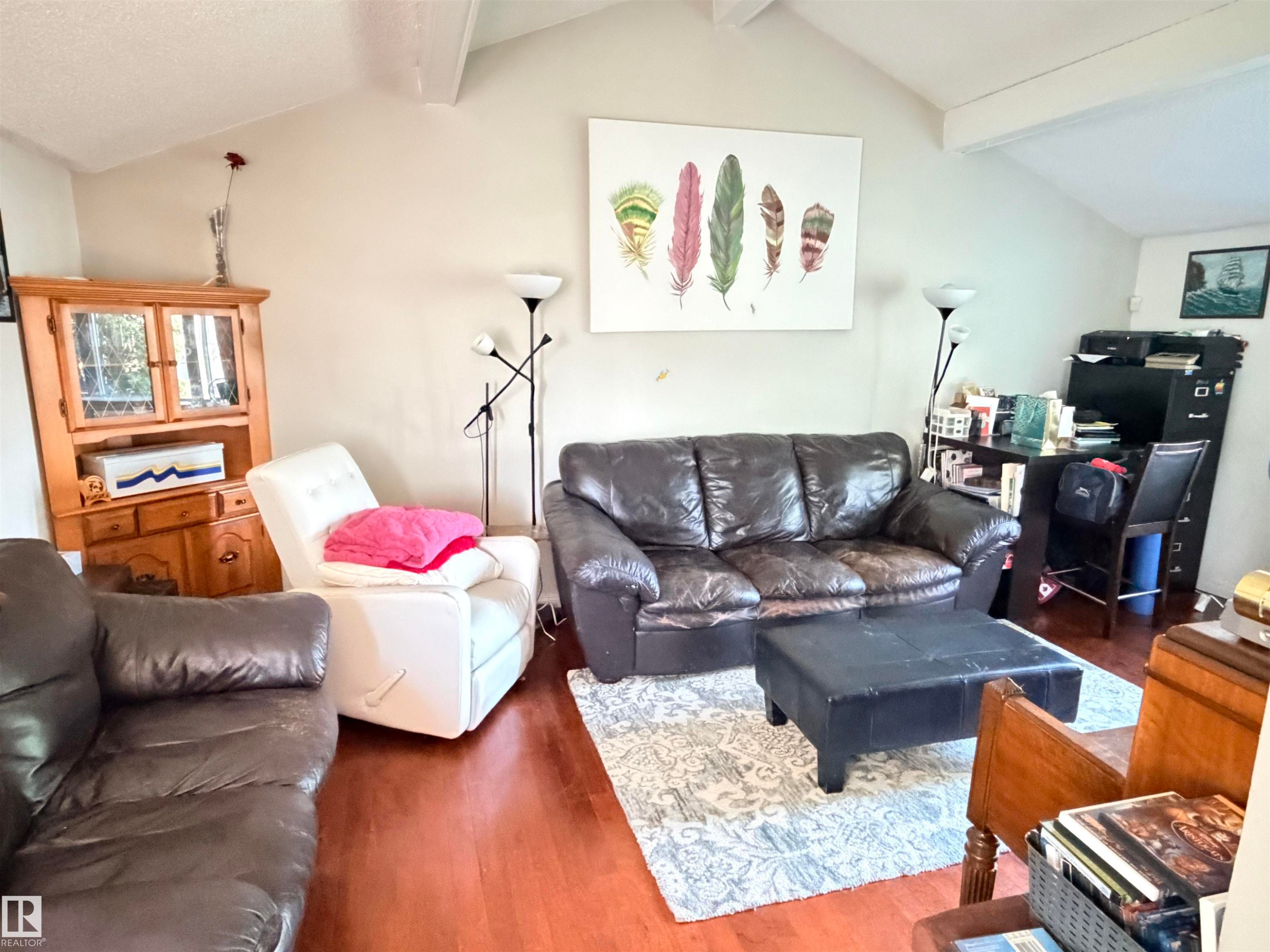Vaulted ceiling featuring exposed beams, wood-finish flooring, and neutral wall tones - 4823 49 Street, Clyde, AB - Indoor Photo Showing Living Room