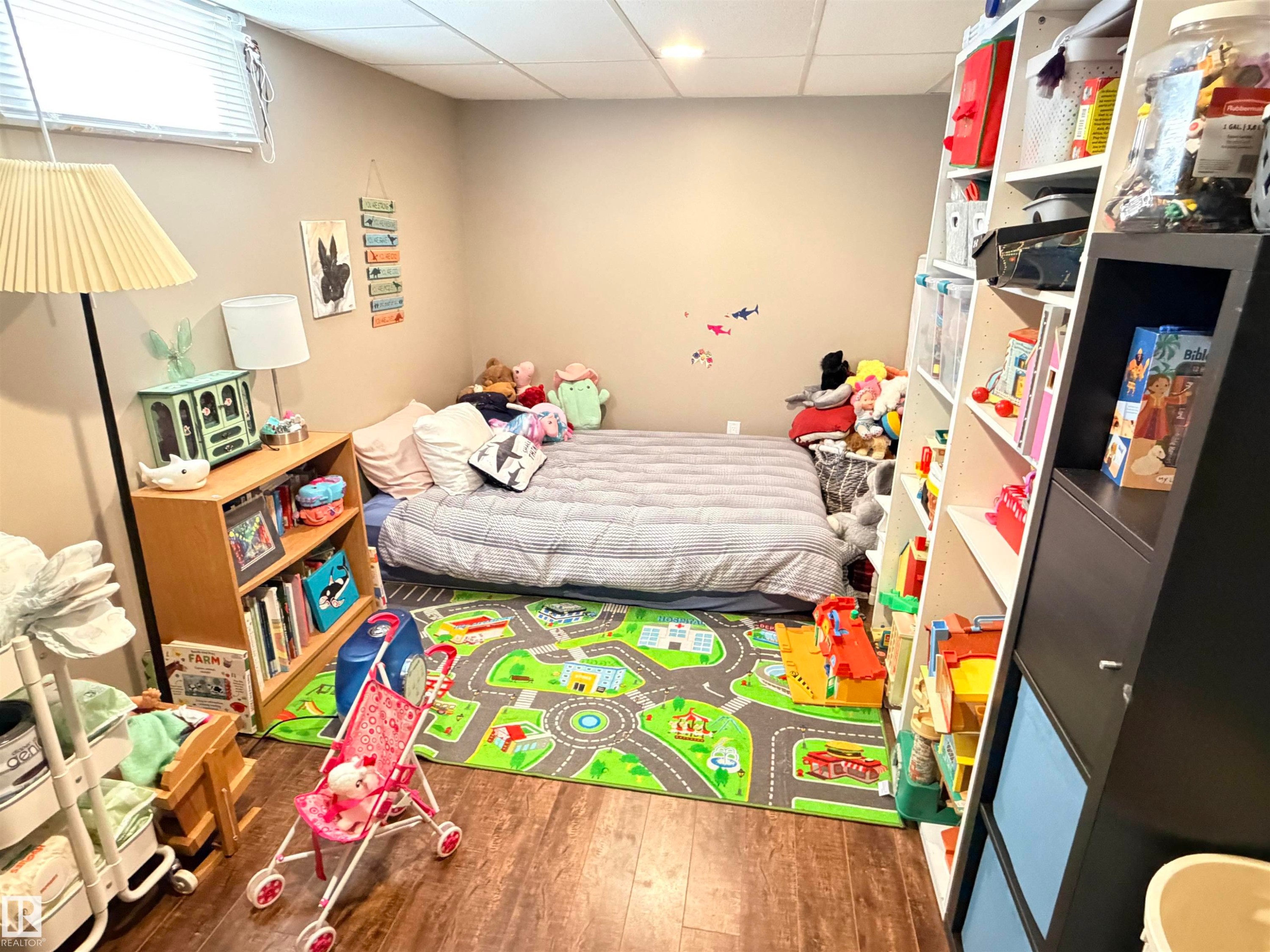 Recreational room featuring wood-finish flooring, neutral wall tones, and a window with blinds - 4823 49 Street, Clyde, AB - Indoor