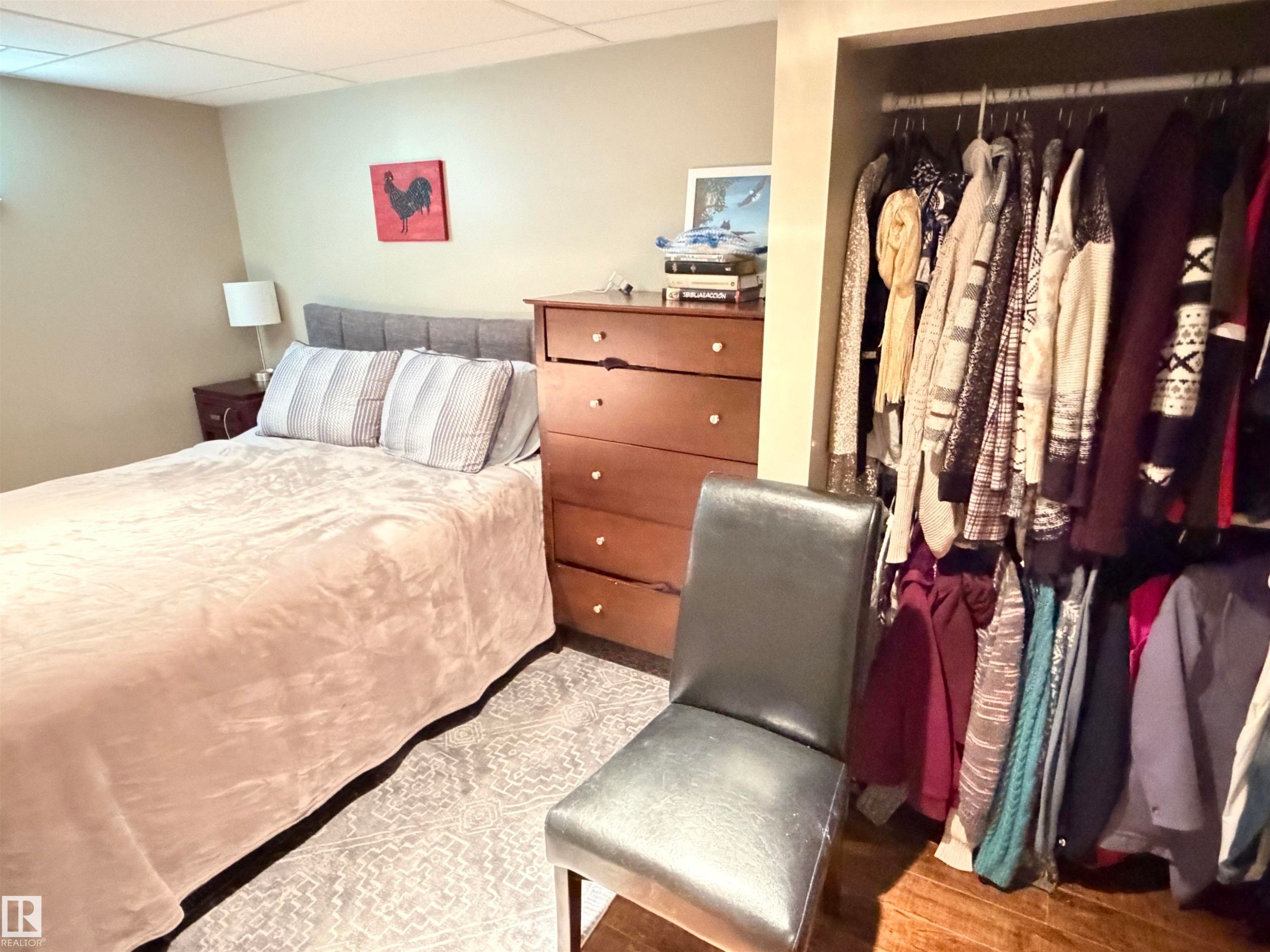 Neutral wall paint, ceiling tiles, and a patterned area rug define this room - 4823 49 Street, Clyde, AB - Indoor Photo Showing Bedroom