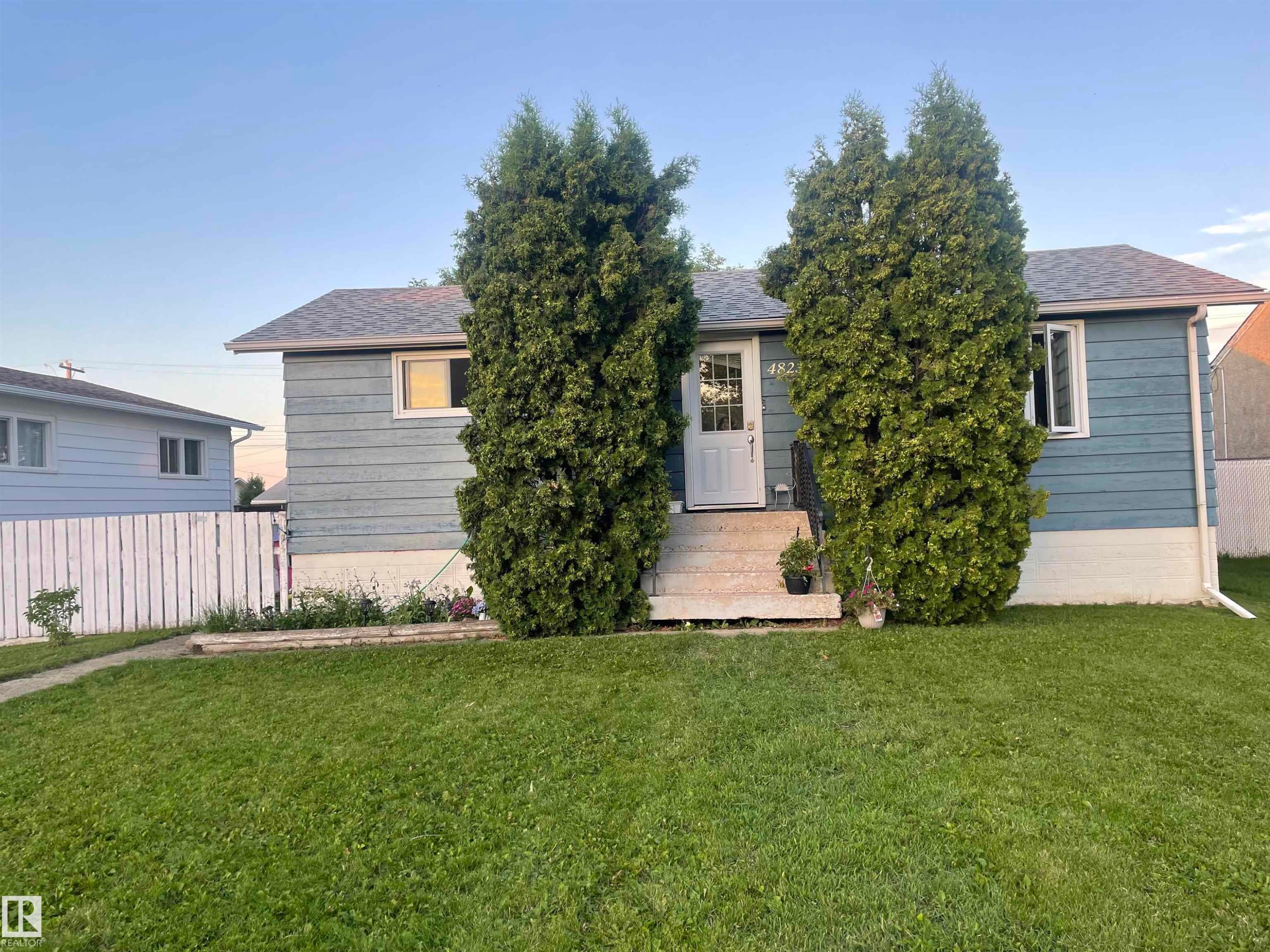 Bungalow with light blue siding, white front door, and white trim windows - 4823 49 Street, Clyde, AB - Outdoor
