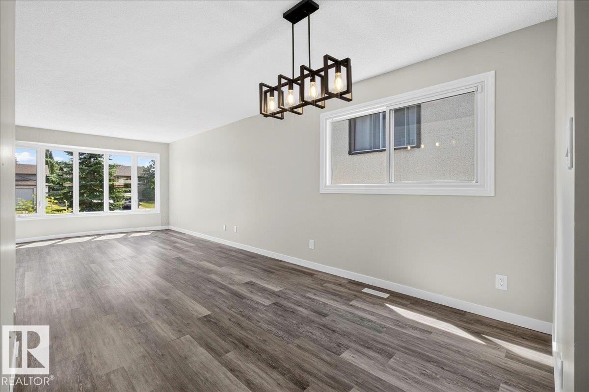 Spacious room featuring wood-finish flooring, light grey walls, and white trim - 4212 32 Avenue Nw, Edmonton, AB - Indoor