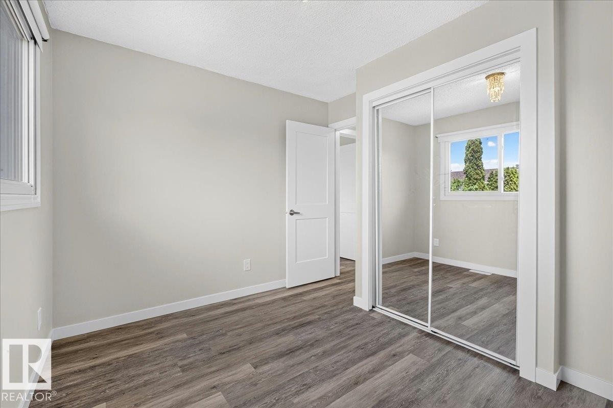 Bedroom featuring wood-finish flooring, light neutral wall paint, white baseboards, and a white ceiling - 4212 32 Avenue Nw, Edmonton, AB - Indoor Photo Showing Other Room