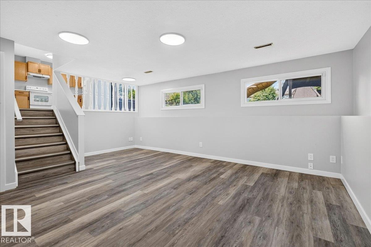 Lower-level living area featuring wood-finish flooring, recessed lighting, and multiple windows - 4212 32 Avenue Nw, Edmonton, AB - Indoor Photo Showing Other Room