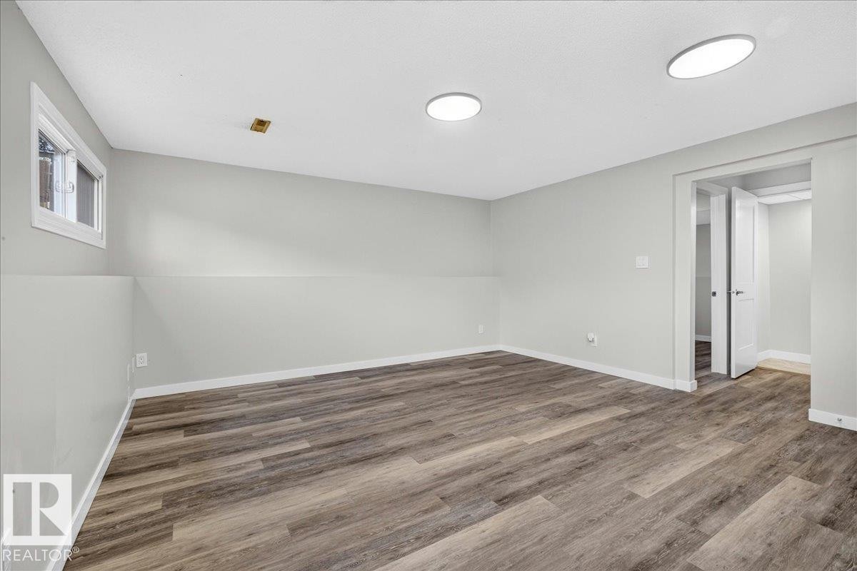 Spacious room featuring wood-finish flooring, light gray walls, white trim, and recessed ceiling lighting - 4212 32 Avenue Nw, Edmonton, AB - Indoor Photo Showing Other Room