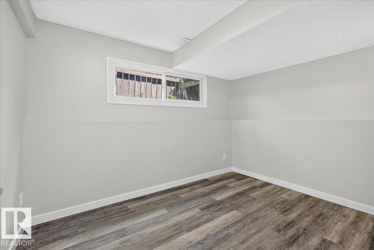 Room featuring wood-finish flooring, light grey walls, white trim, and a white-framed window - 4212 32 Avenue Nw, Edmonton, AB - Indoor Photo Showing Other Room
