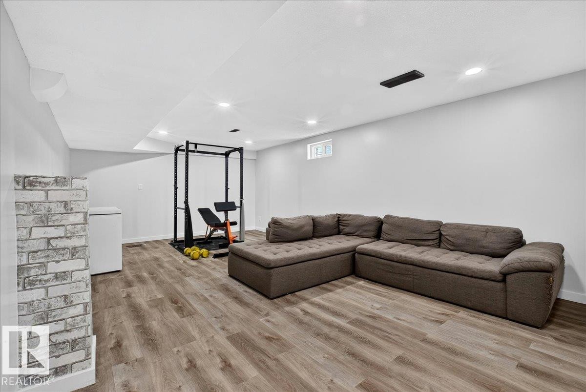 Spacious lower-level room featuring wood-finish flooring, white painted walls, and recessed ceiling lighting - 4212 32 Avenue Nw, Edmonton, AB - Indoor