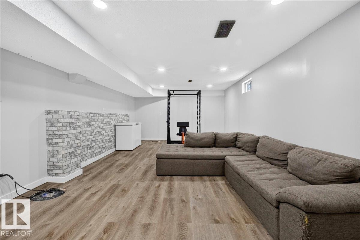 Finished lower level featuring recessed lighting, durable wood-finish flooring, and a decorative faux brick accent wall - 4212 32 Avenue Nw, Edmonton, AB - Indoor Photo Showing Living Room
