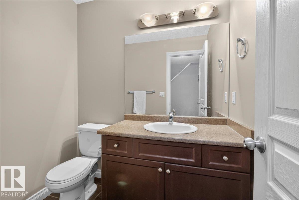 Bathroom featuring a wood-finish vanity with a light-colored countertop, an undermount sink, and a single-handle faucet - 5110 168A Avenue Nw, Edmonton, AB - Indoor Photo Showing Bathroom
