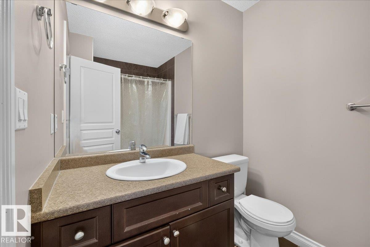 Bathroom with a dark wood-finish vanity, integrated sink, and light-toned countertop - 5110 168A Avenue Nw, Edmonton, AB - Indoor Photo Showing Bathroom