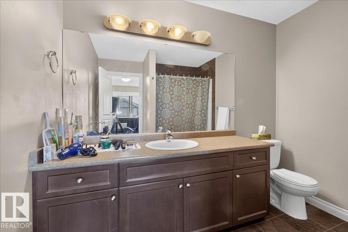 Bathroom featuring a spacious vanity with a built-in sink, ample storage cabinetry, and an expansive mirror - 5110 168A Avenue Nw, Edmonton, AB - Indoor Photo Showing Bathroom