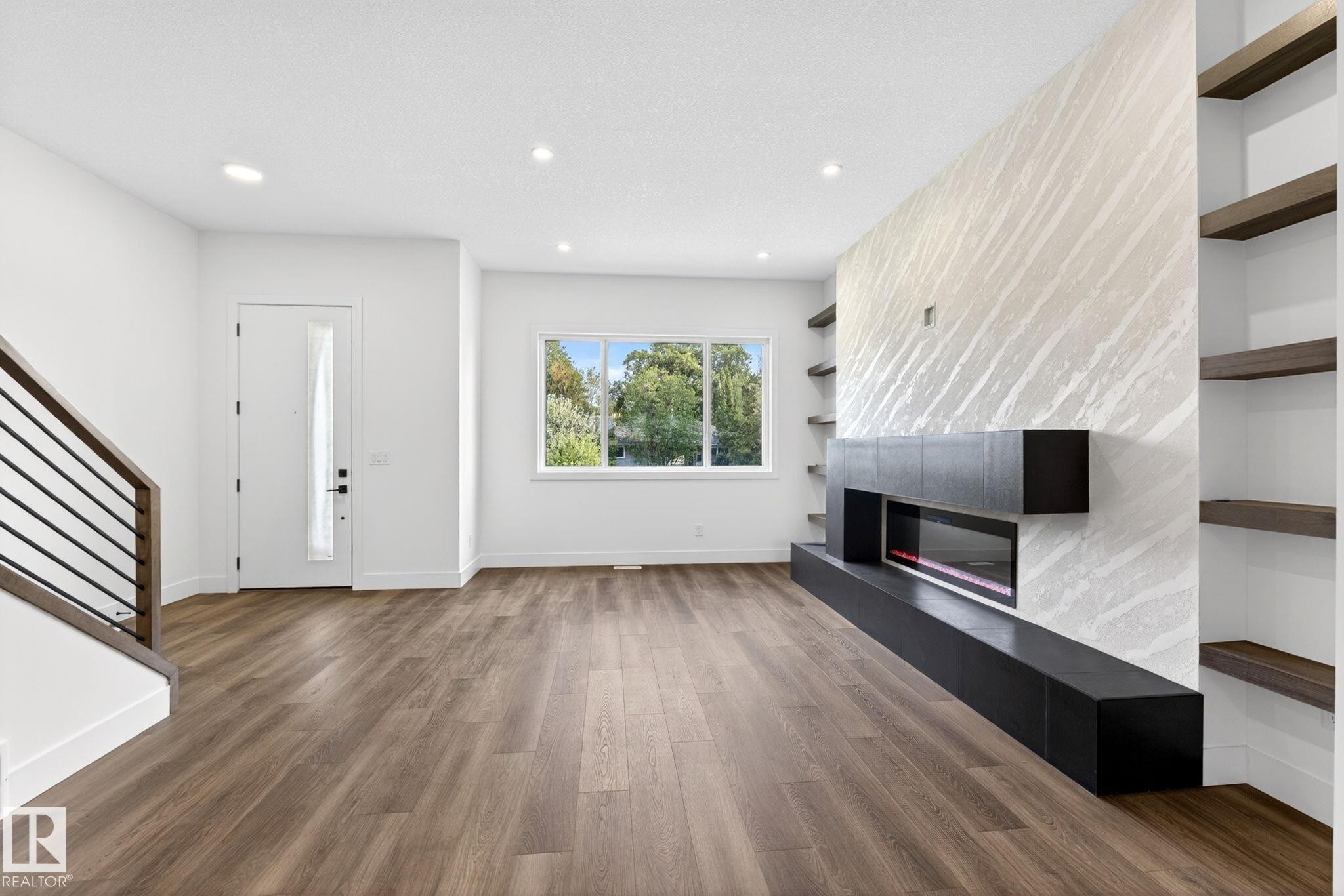 Modern living area featuring wood-finish flooring, a contemporary fireplace with a linear insert, and built-in shelving - 5308 103A Avenue, Edmonton, AB - Indoor With Fireplace