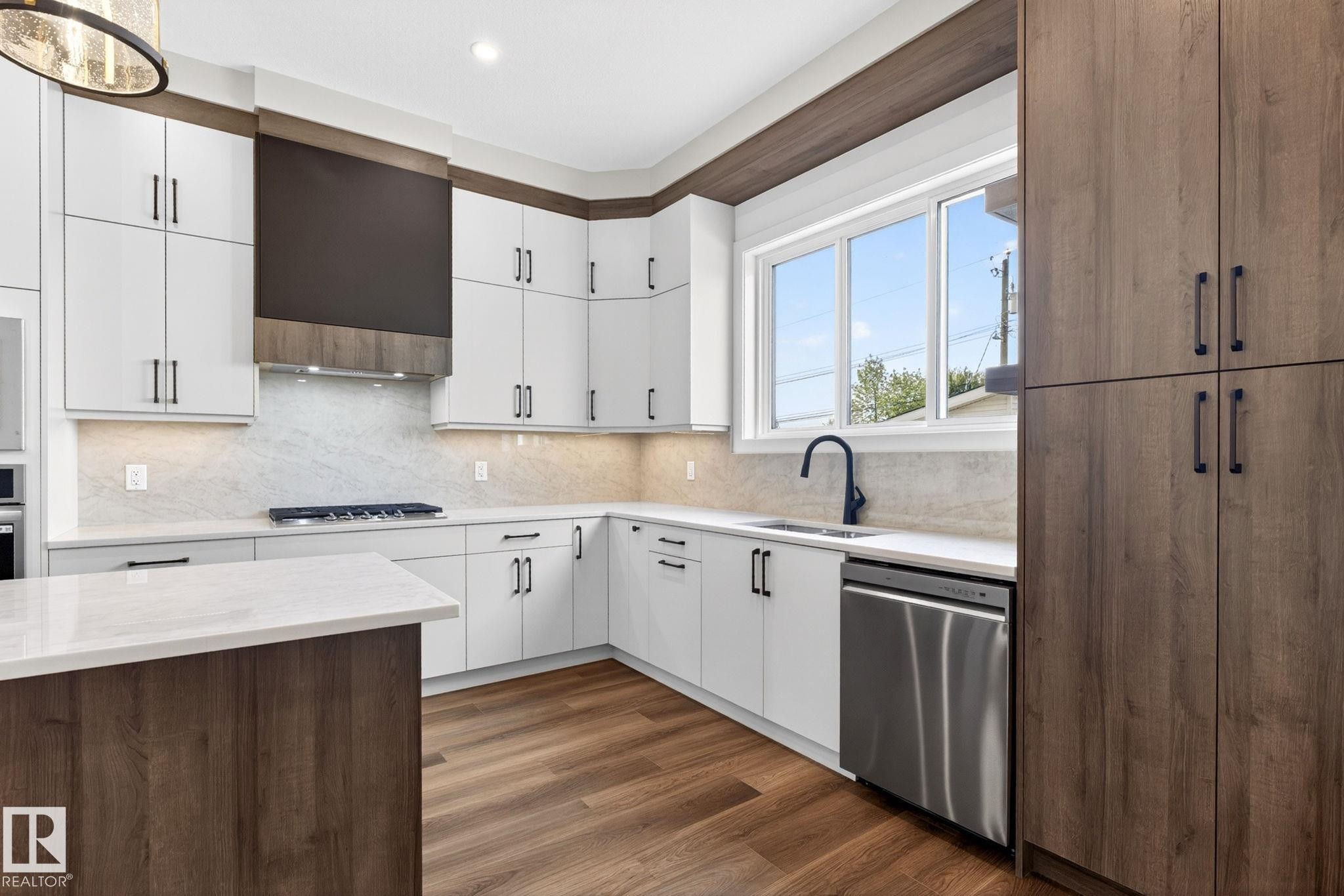 Modern kitchen featuring white cabinetry, wood-finish flooring, and a large window - 5308 103A Avenue, Edmonton, AB - Indoor Photo Showing Kitchen With Upgraded Kitchen