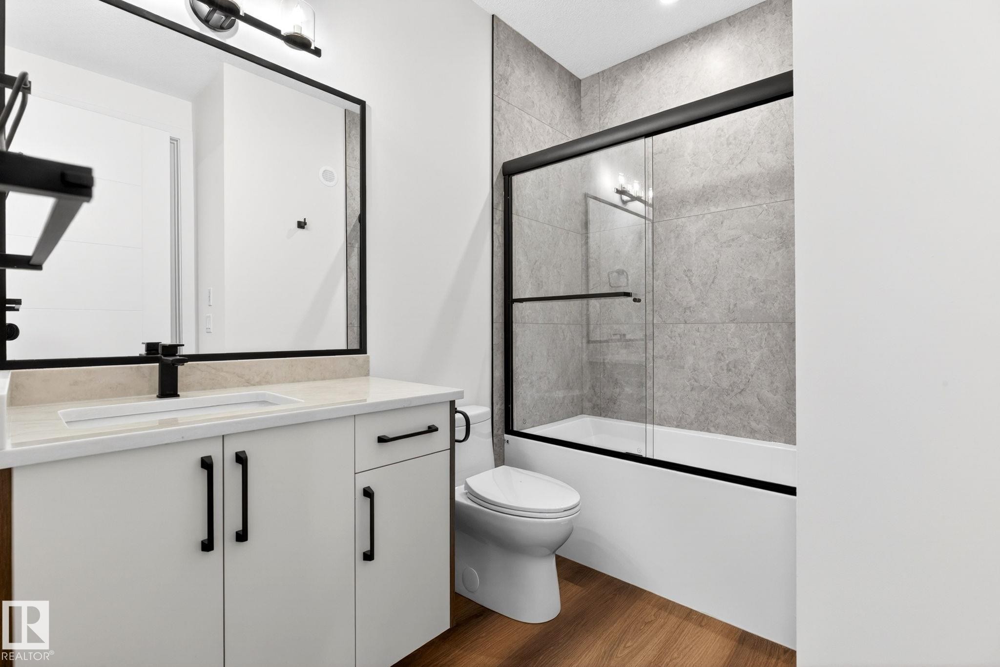 Bathroom featuring a white vanity with integrated sink, black hardware, and a stone countertop - 5308 103A Avenue, Edmonton, AB - Indoor Photo Showing Bathroom