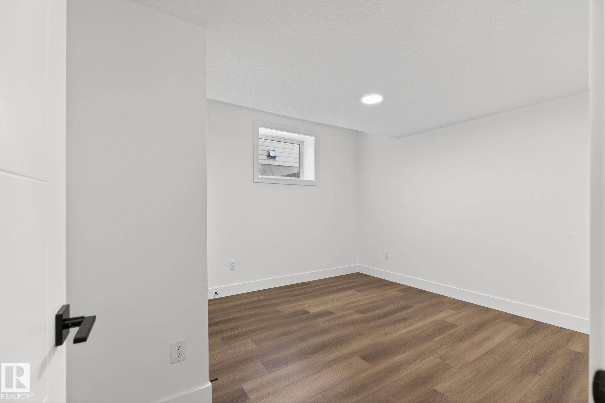 Bright room featuring wood-finish flooring, white baseboards, and a neutral color palette - 5308 103A Avenue, Edmonton, AB - Indoor Photo Showing Other Room