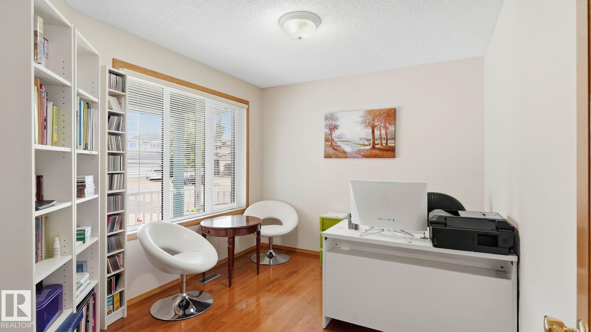 Dedicated room with wood-finish flooring, a large window with blinds, and neutral wall paint - 125 Dechene Road Nw, Edmonton, AB - Indoor Photo Showing Other Room